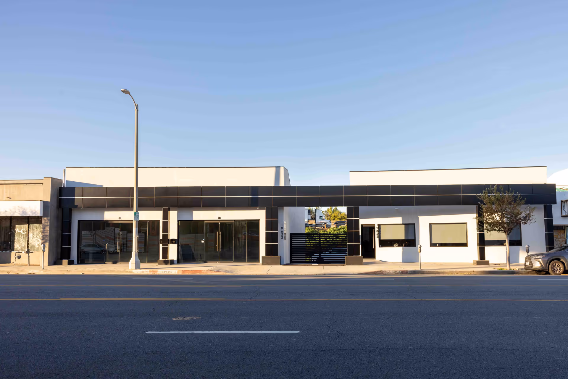 Modern, single-story storefronts line a street with glass windows and black accents.