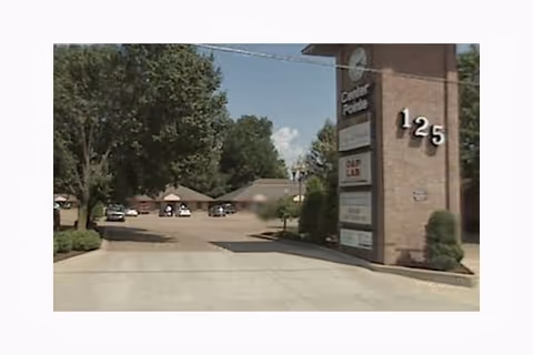 Exterior view of a facility entrance with a tall sign and driveway.