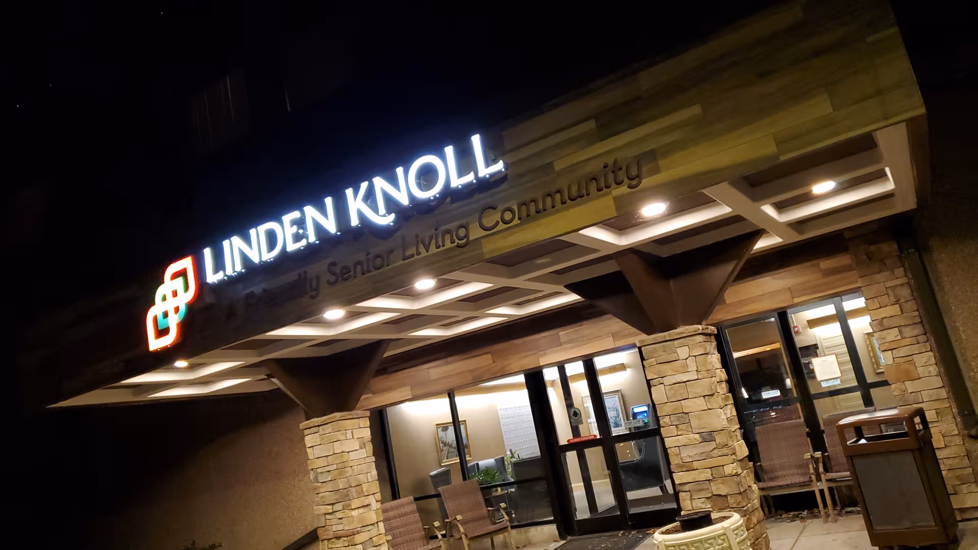 Night exterior of Linden Knoll entrance with stone columns and illuminated sign.