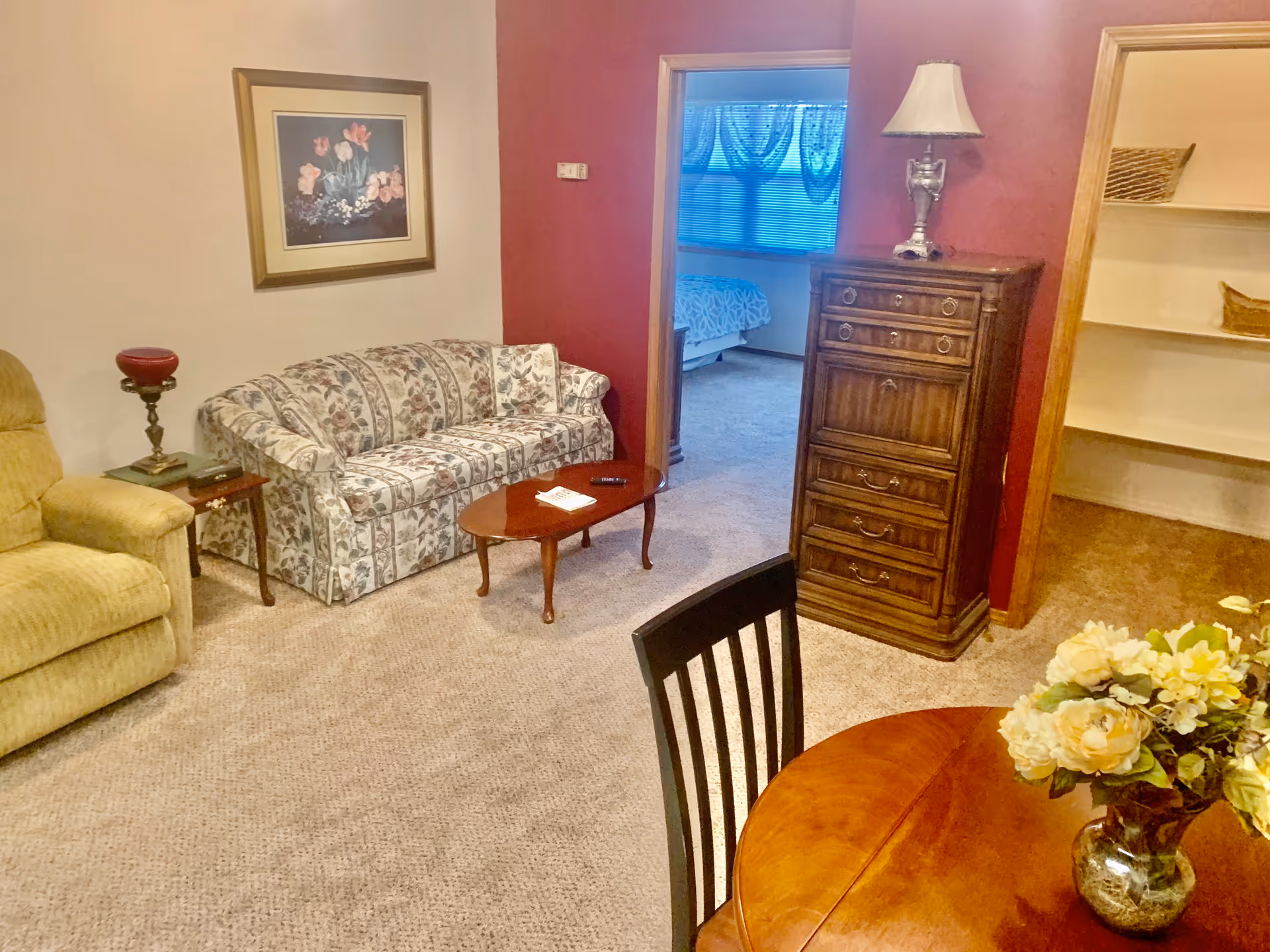 Cozy living room with floral sofa, coffee table, and wooden dresser.
