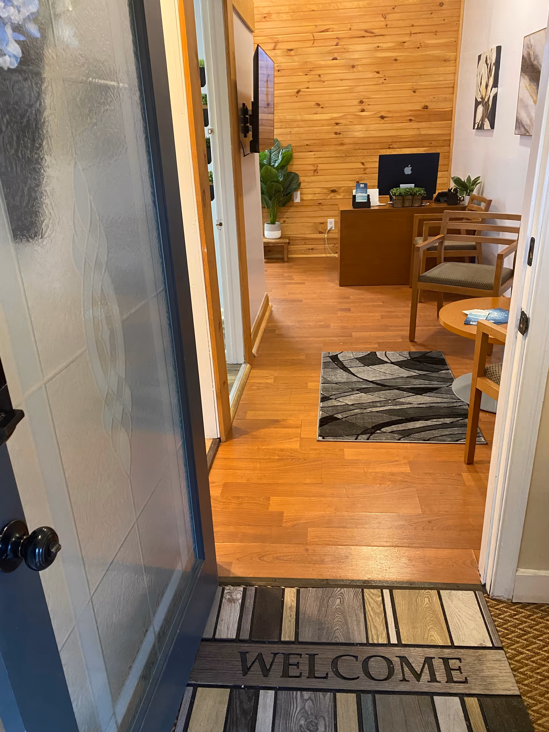 View from an open door into a warm reception area with a desk and seating.