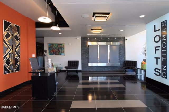 Modern indoor lobby area with a reception desk and black tiled floor.