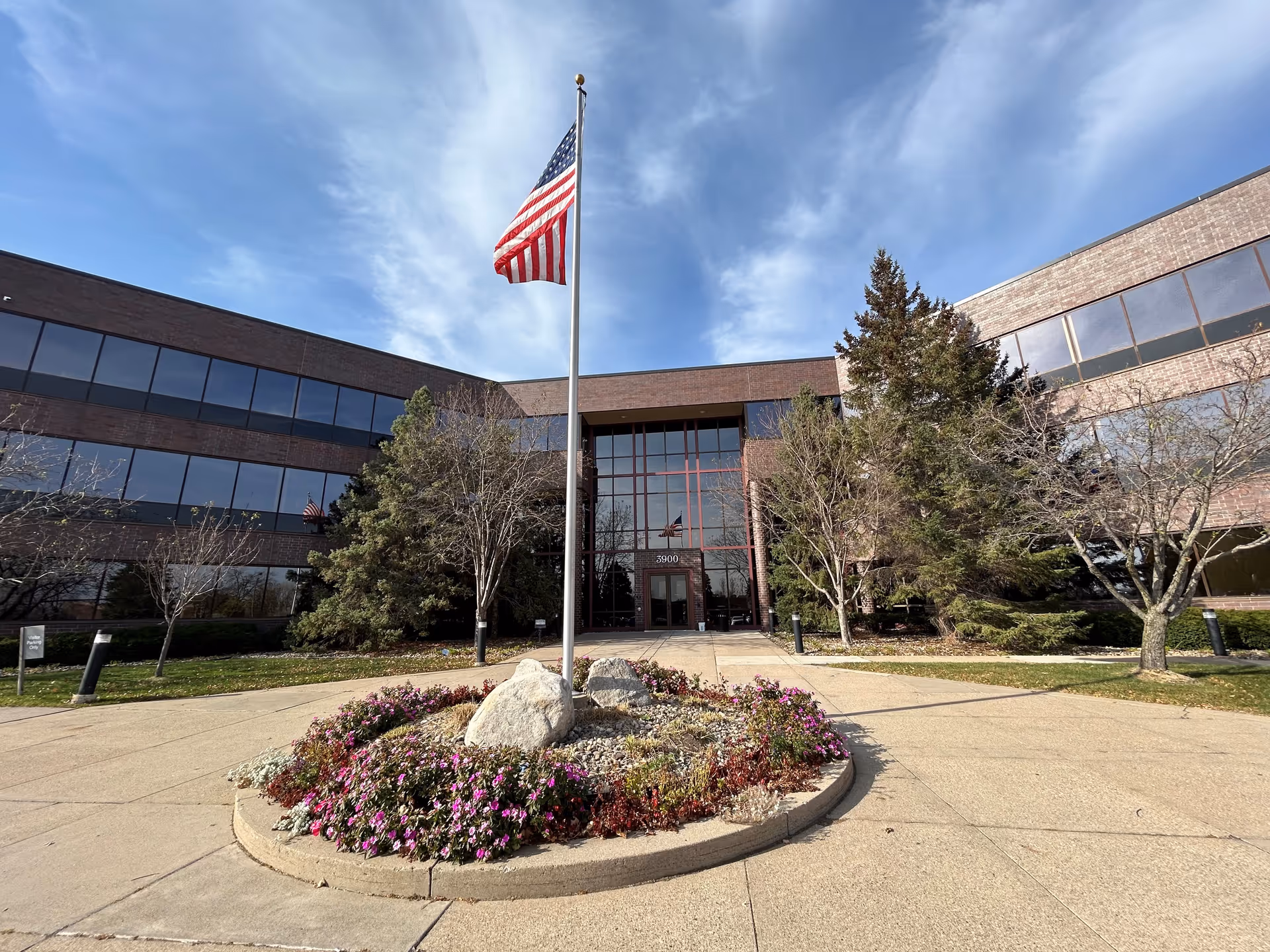 TRU Healthcare exterior: brick building with glass windows, flagpole, and circular flower bed.
