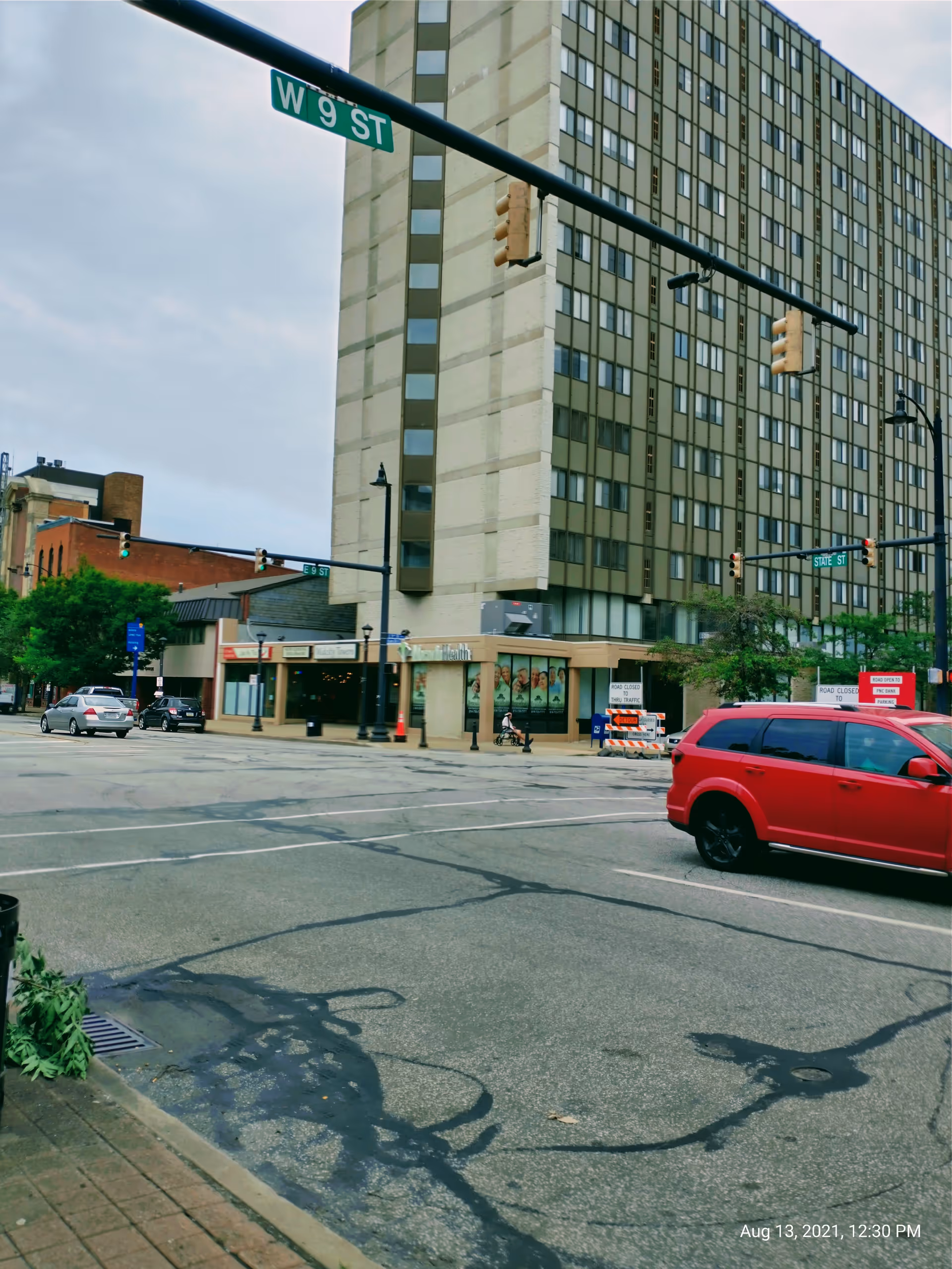 Tall city building overlooking a busy intersection with storefronts.
