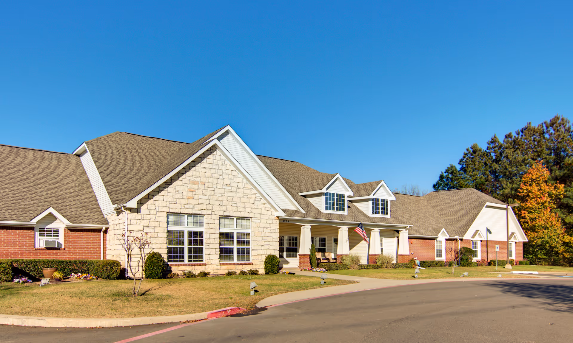 Brookdale Texarkana senior living facility exterior with lawn, entrance, and clear blue sky.