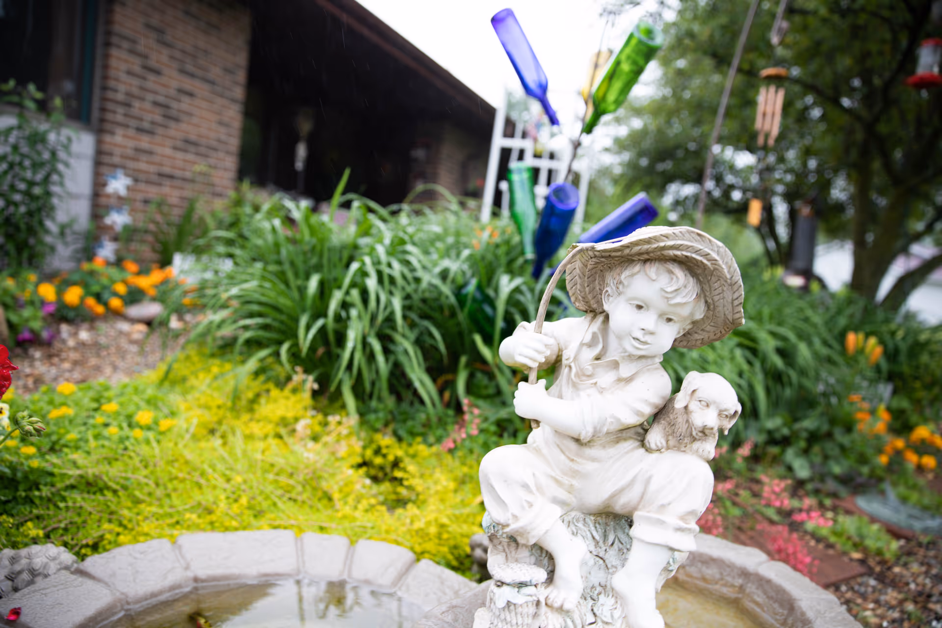 Colorful garden statue of a child with hat and small animal beside a fountain.