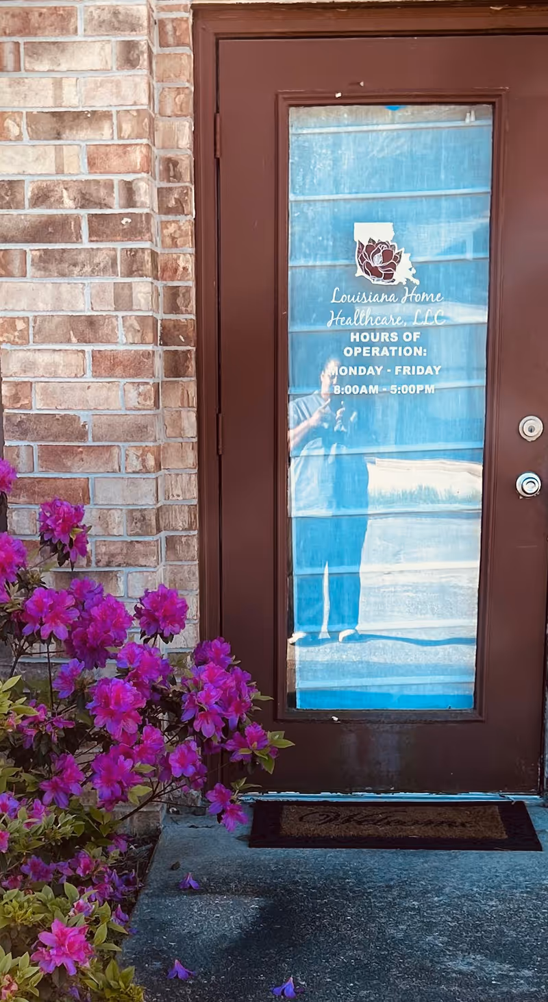 Exterior door of Louisiana Home Healthcare LLC with glass panel and purple flowers outside.