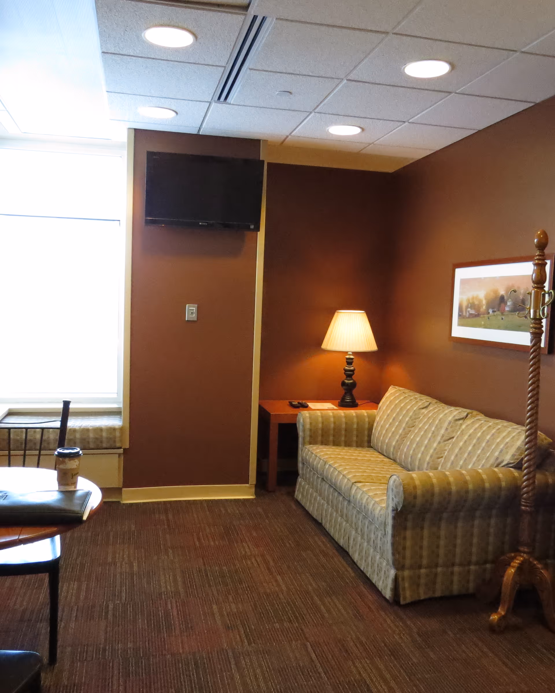 Cozy interior living room with sofa, lamp, coffee table, and wall TV.