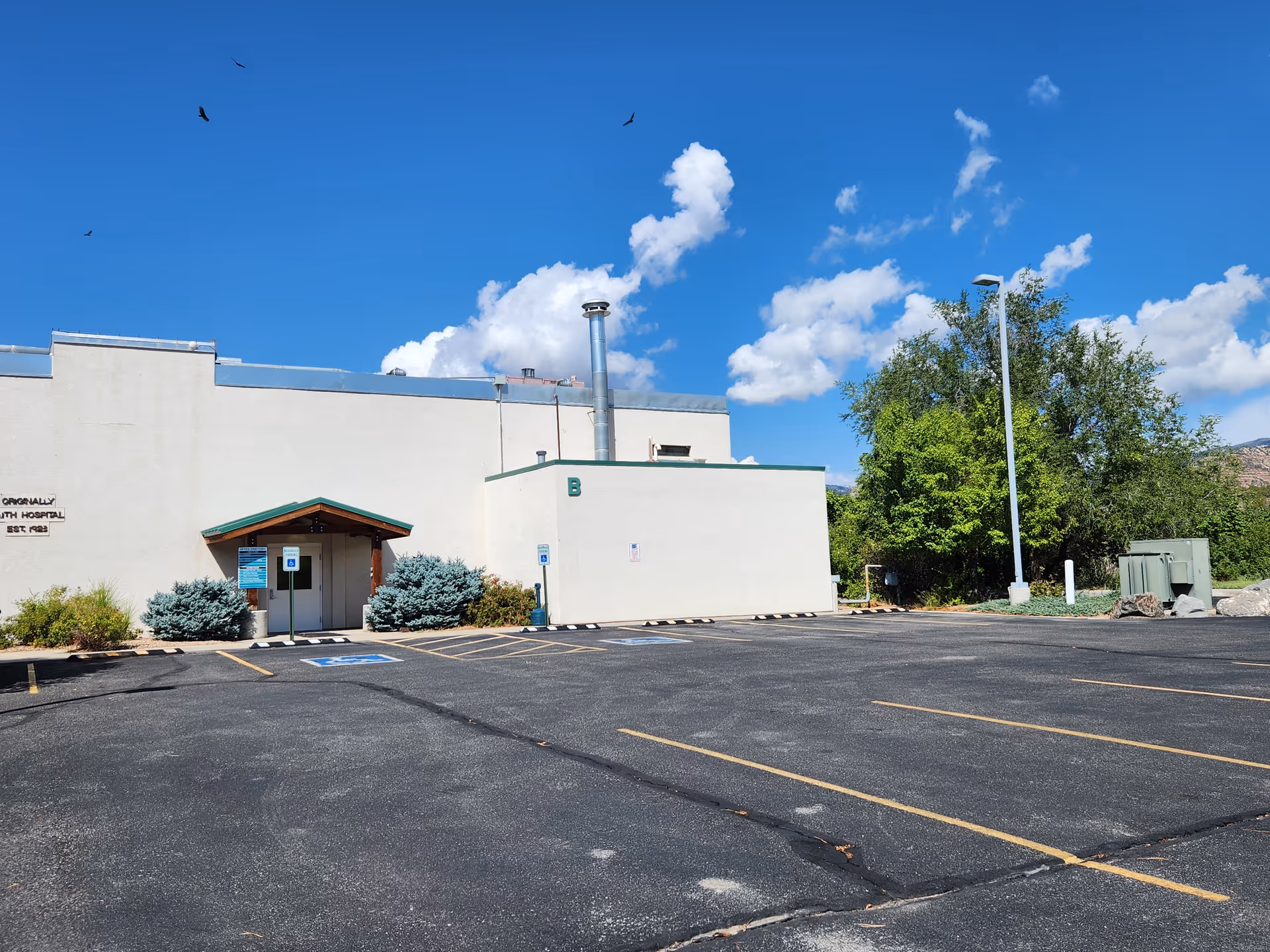 HopeWest Administrative Offices building with a small entrance, parking lot, and clear blue sky.