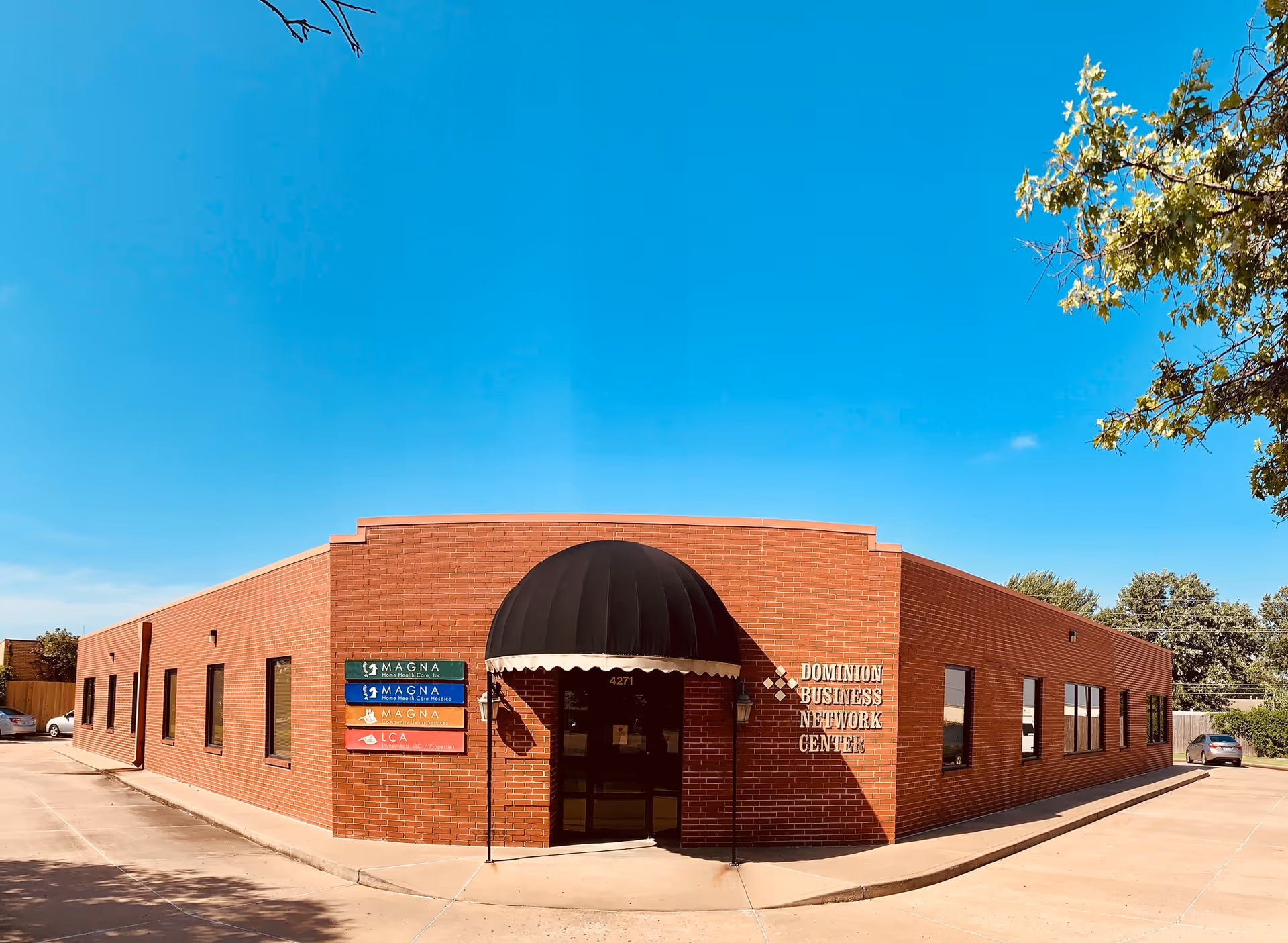 Brick, single-story facility exterior with a black rounded entrance canopy and blue sky.