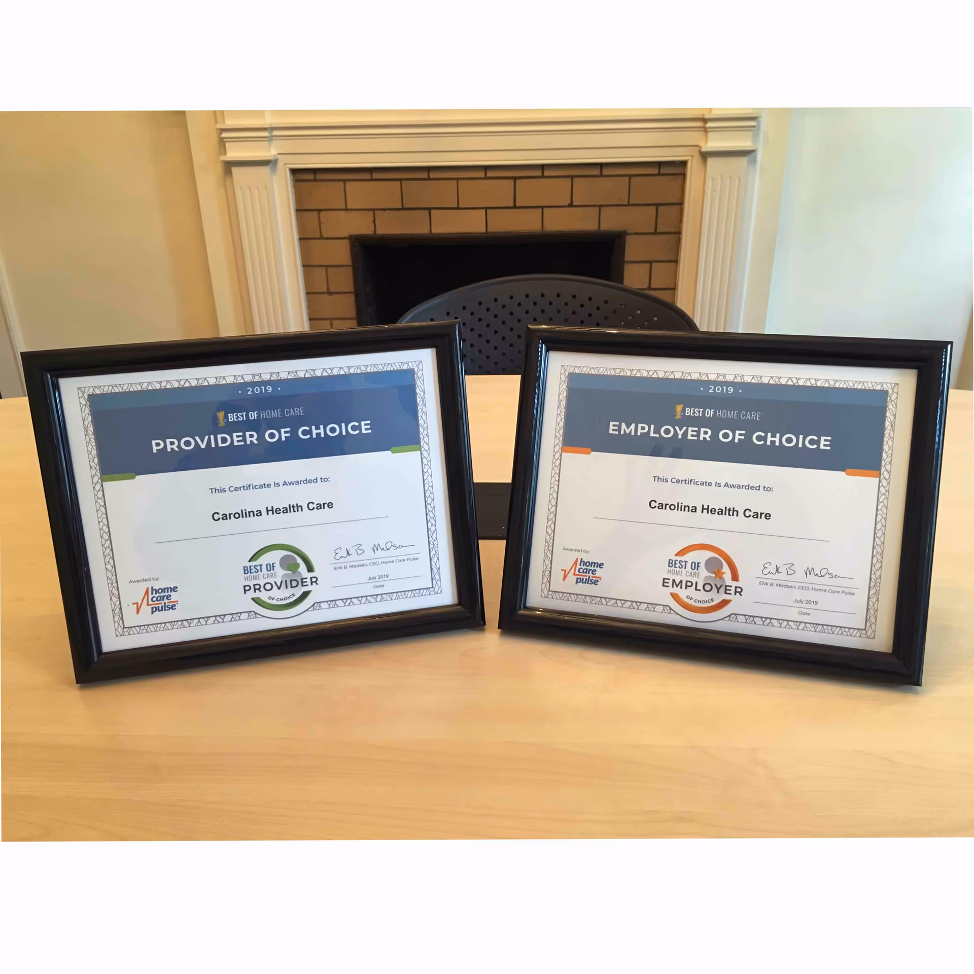 Two framed awards on a table in front of a fireplace.