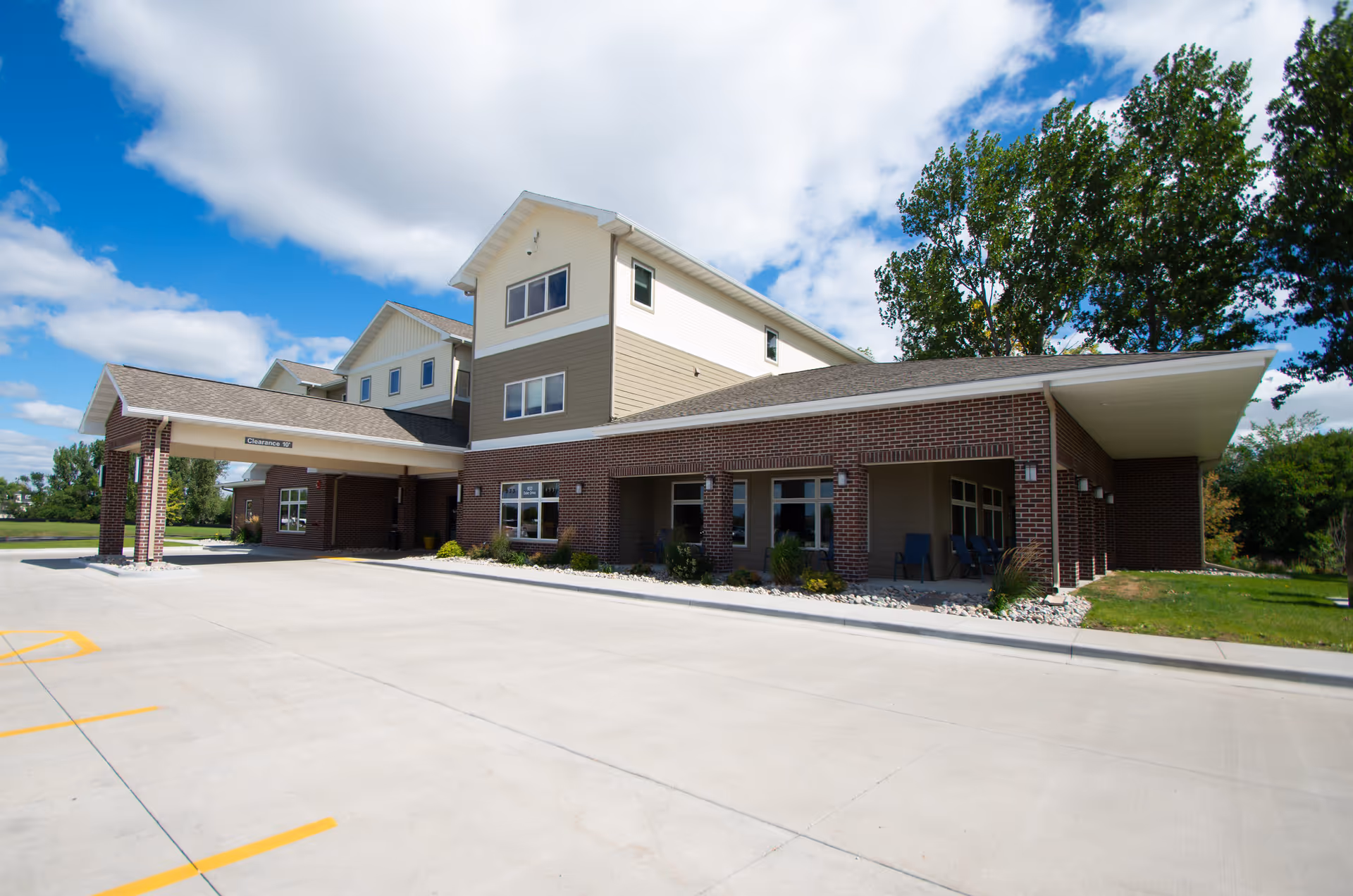 Exterior view of Sunshine Hospitality Home, a brick senior living facility with covered entrance.