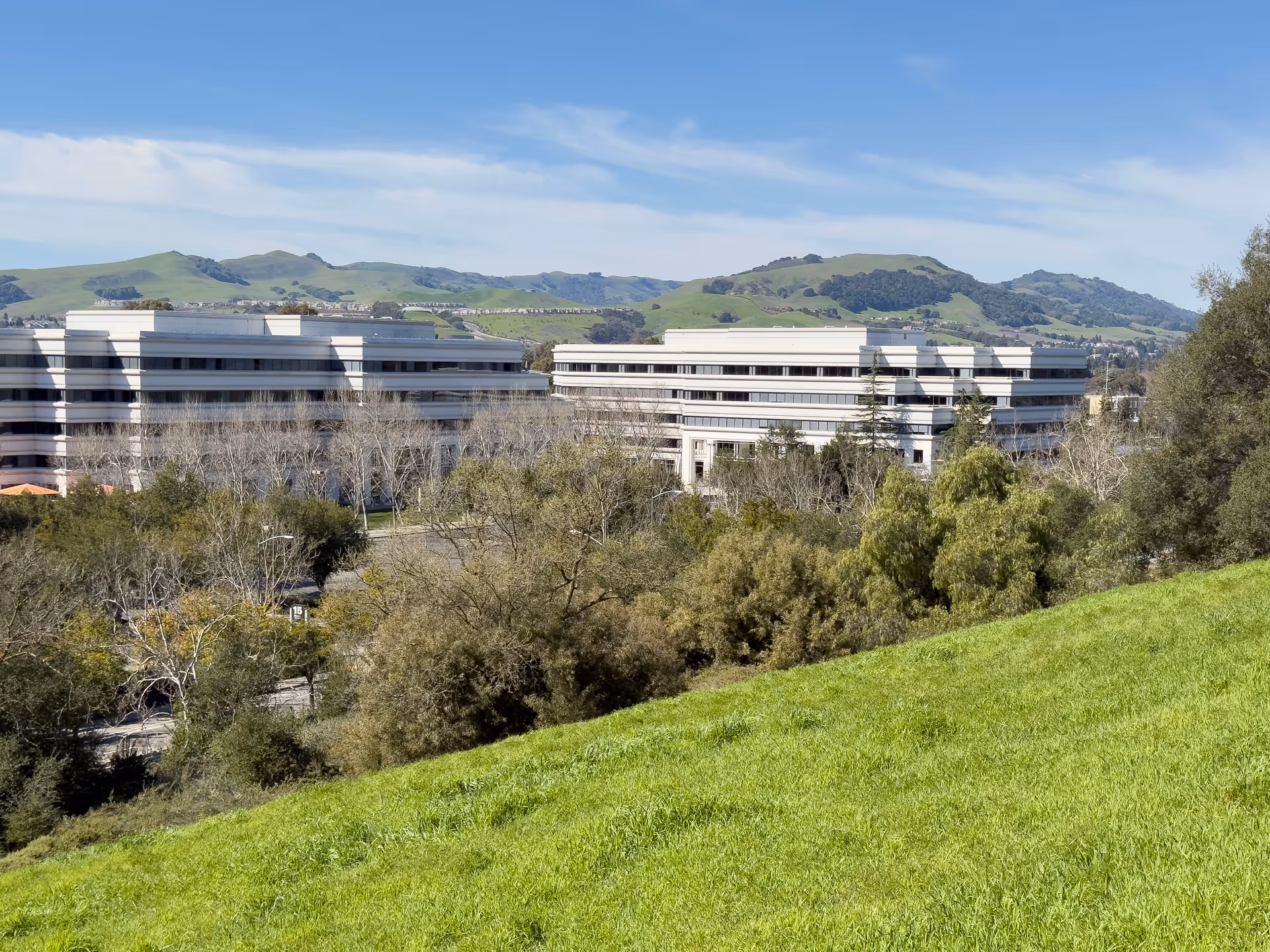 Exterior view of a multi-story medical center with hills in the distance.