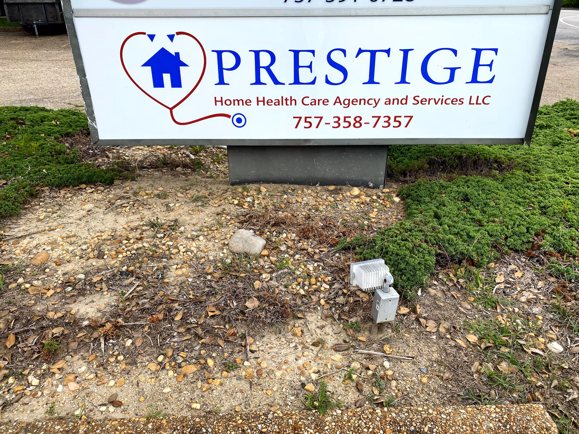 Outdoor sign for Prestige Home Health Care Agency and Services LLC on landscaped ground.