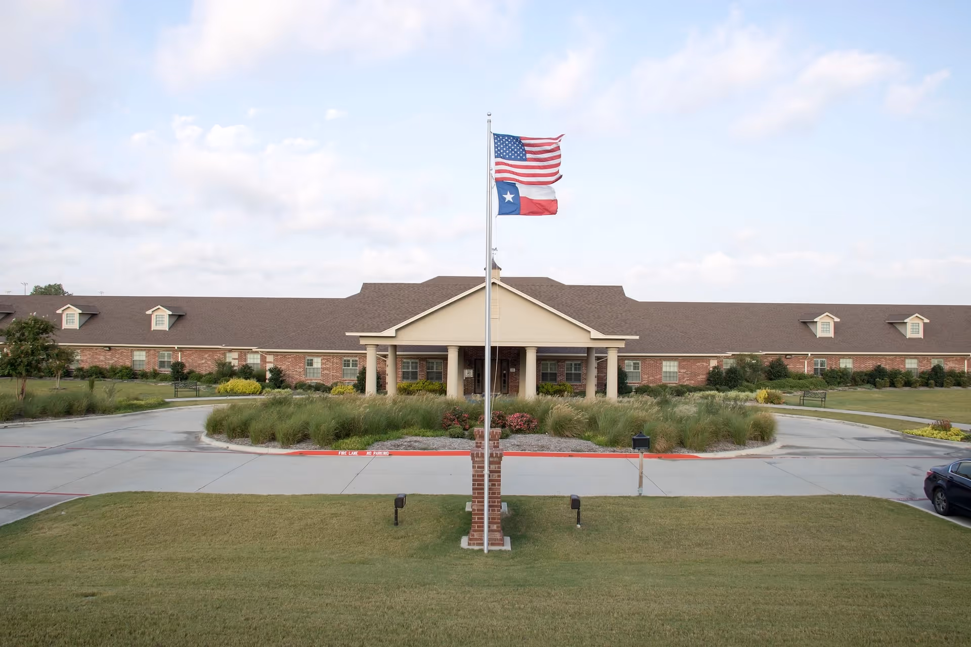 Exterior of Heritage House at Keller Rehab & Nursing with flagpole and entrance.