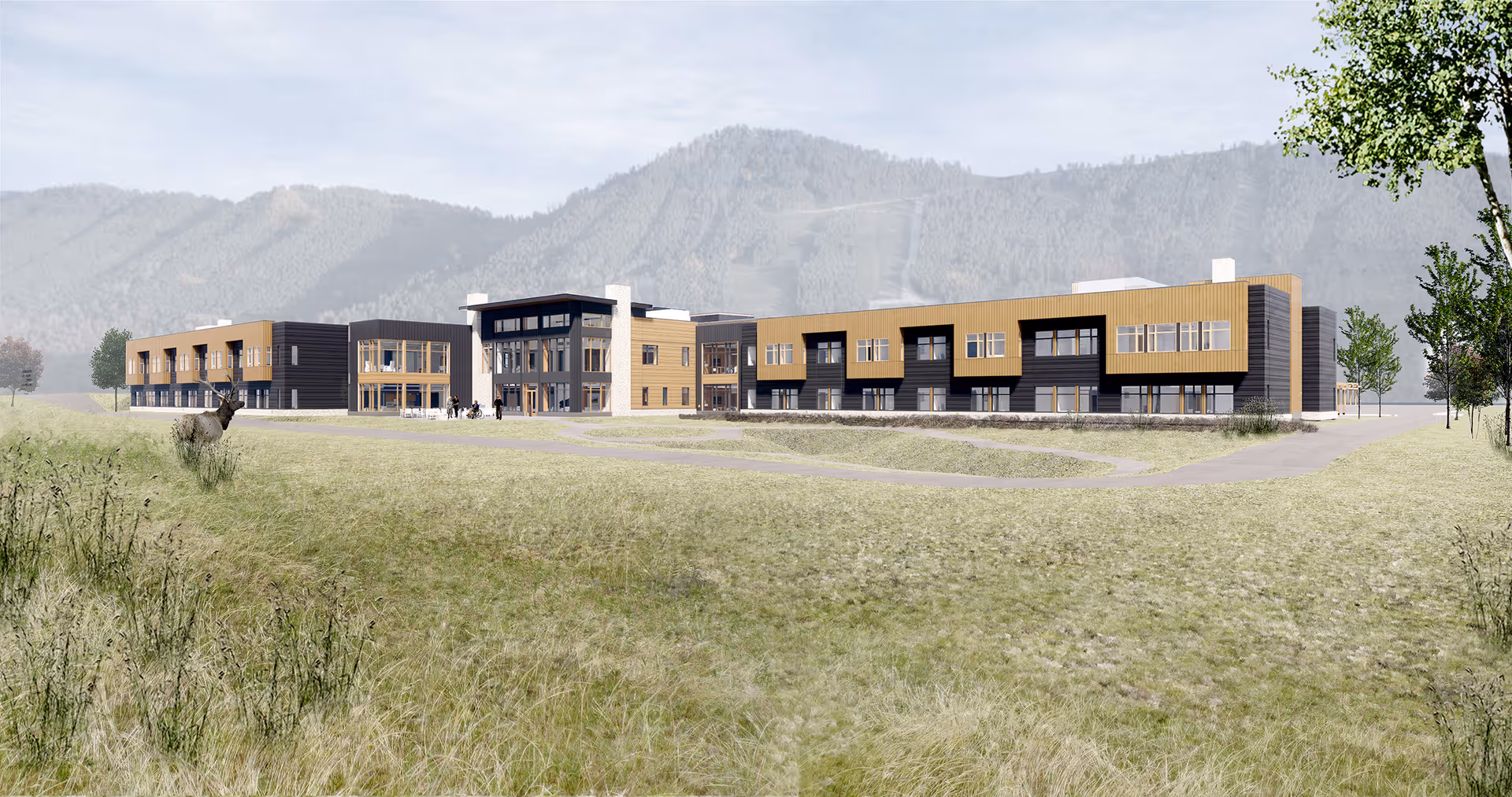 A modern senior living center exterior with multiple wings and mountain backdrop.