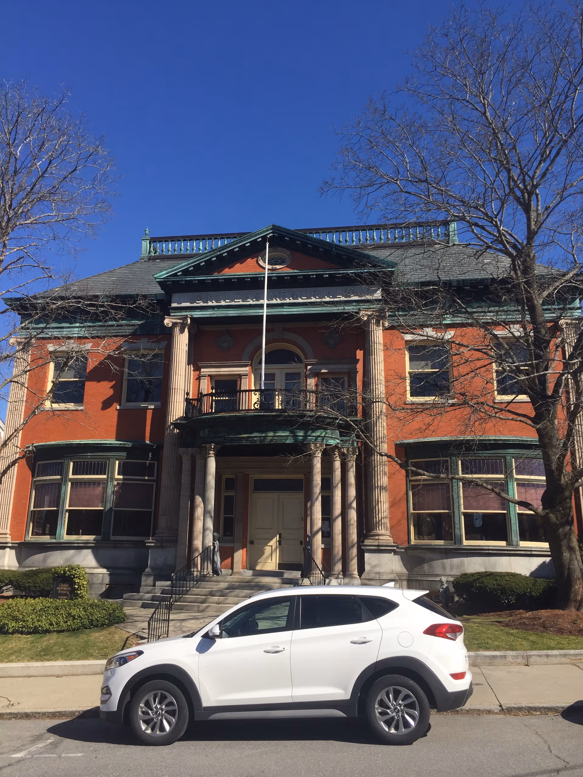 Front facade of Corcoran House Assisted Living with red brick exterior and a white car parked.