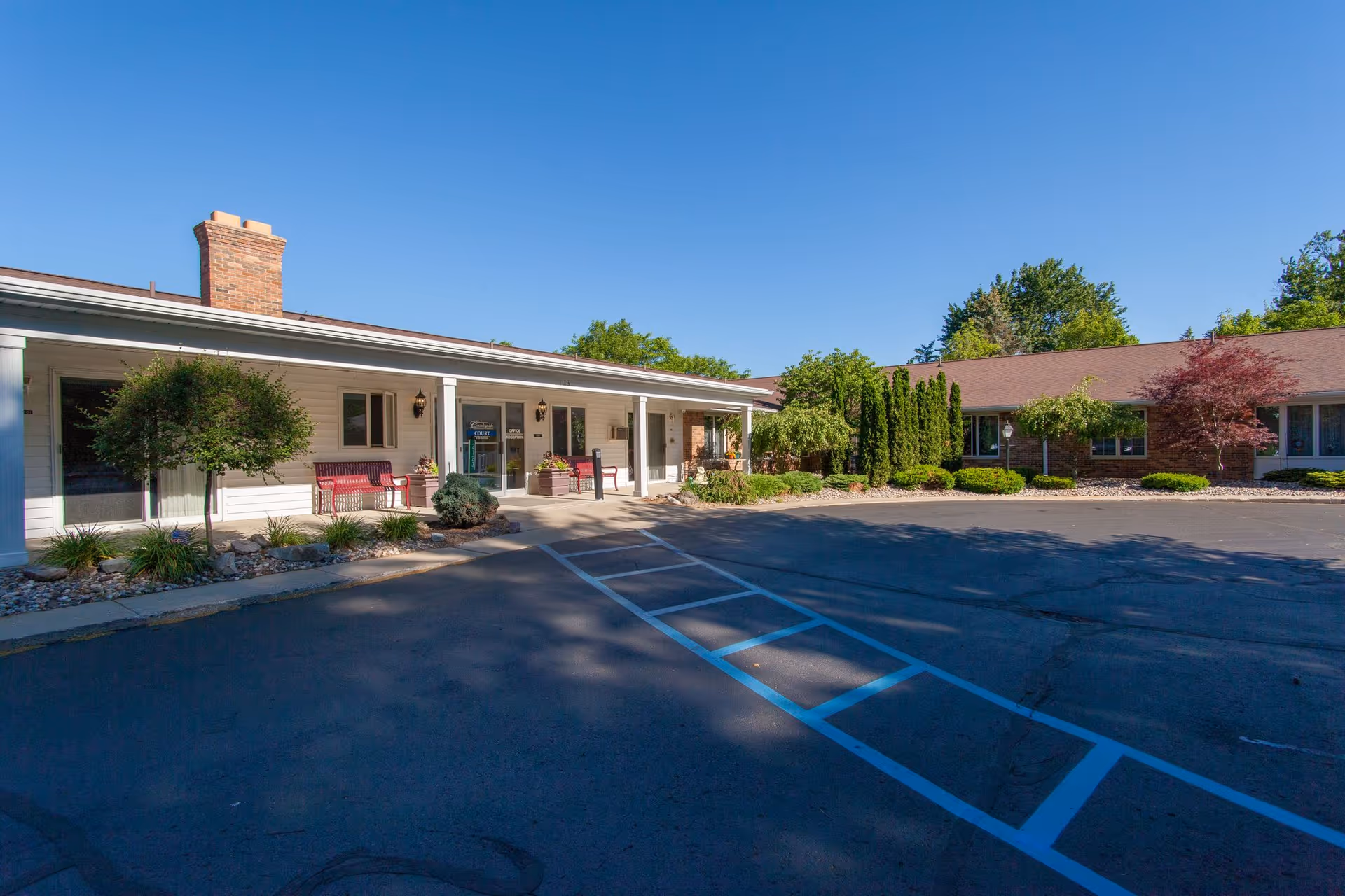 Exterior view of Ganton's Countryside Retirement Community with entrance, benches, and parking.