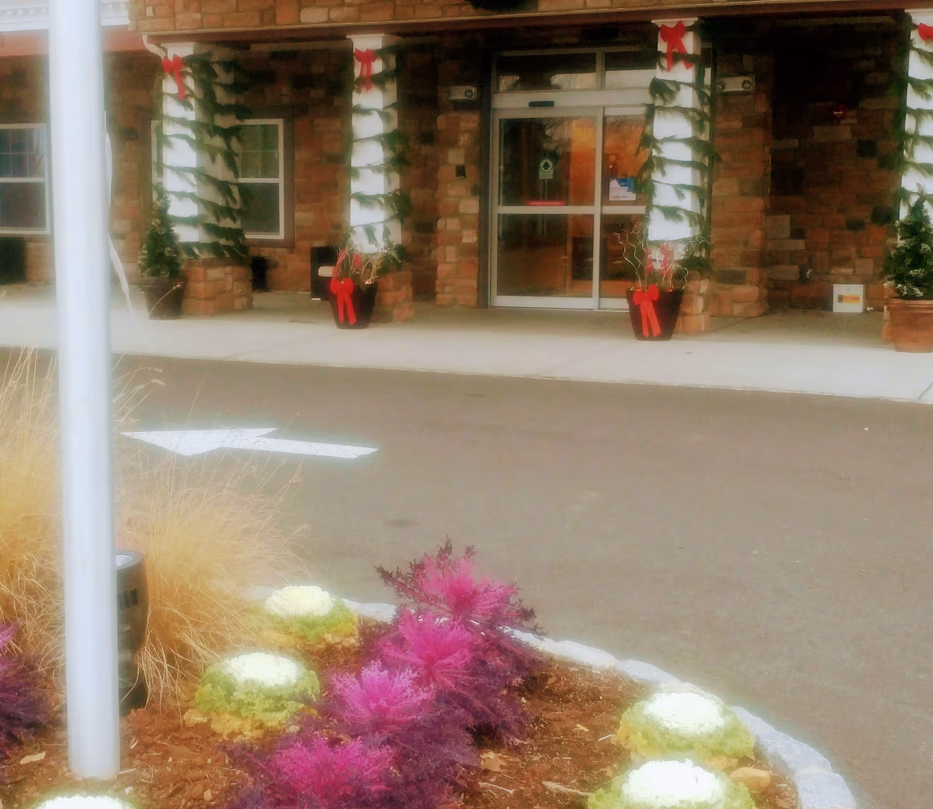 Front entrance of CareOne at Somerset Valley Assisted Living with holiday garlands and planters