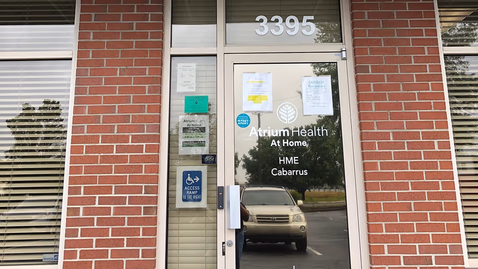 Brick building exterior with a glass entrance door labeled Atrium Health At Home and 3395.