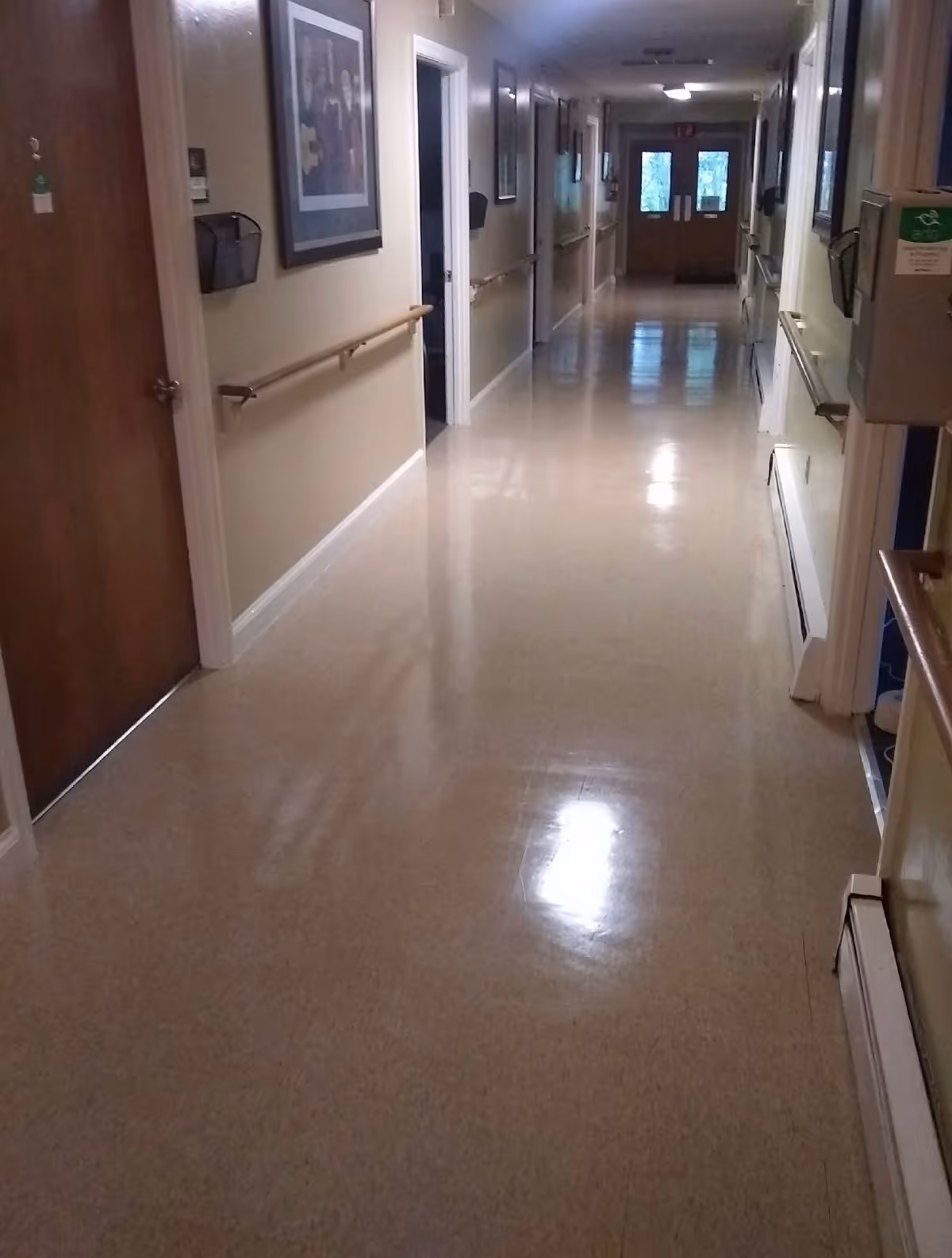 Long, well-lit hallway inside a senior living facility with wall art and doors.