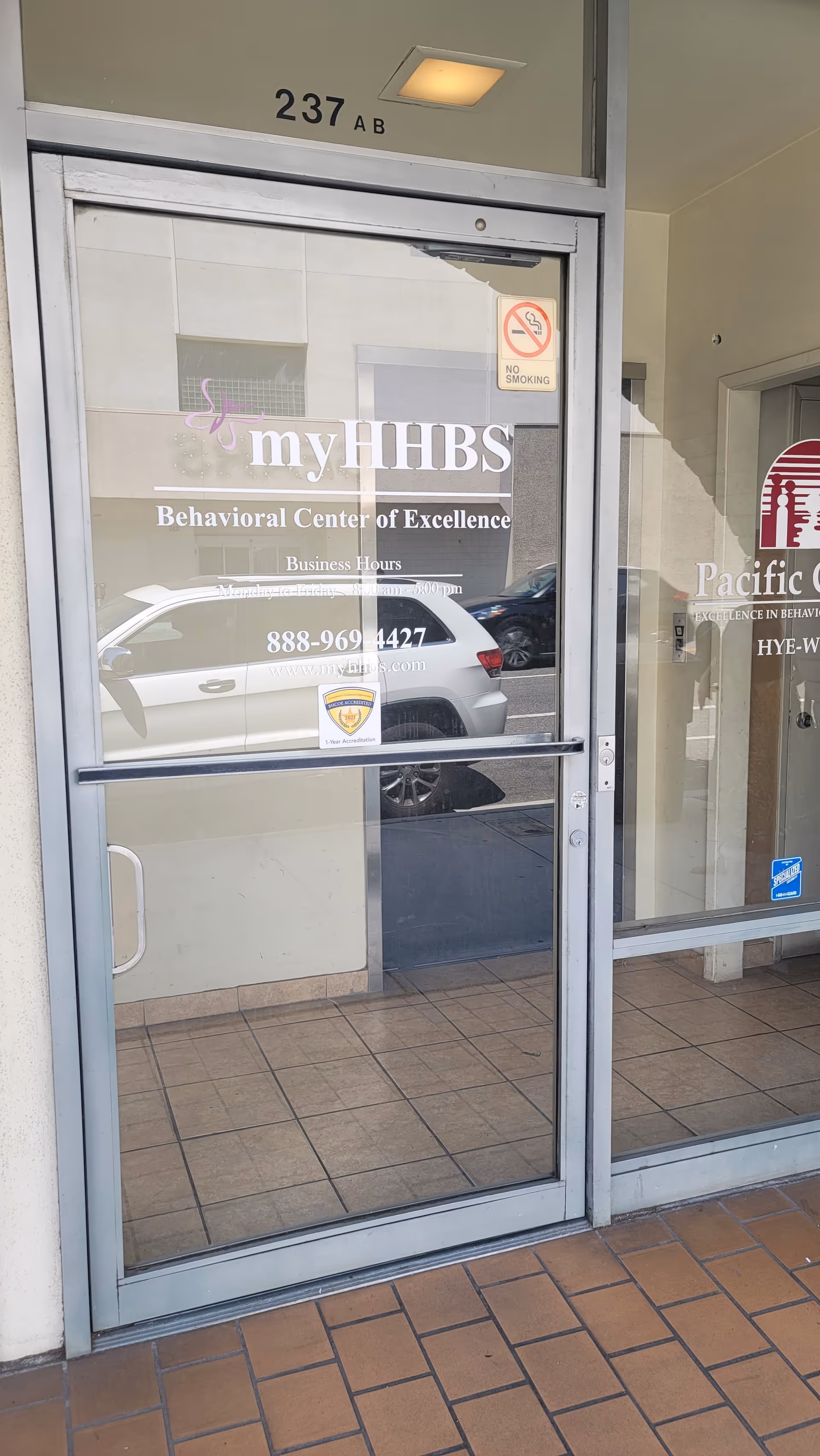 Glass storefront door displaying myHHBS Behavioral Center of Excellence signage with reflections