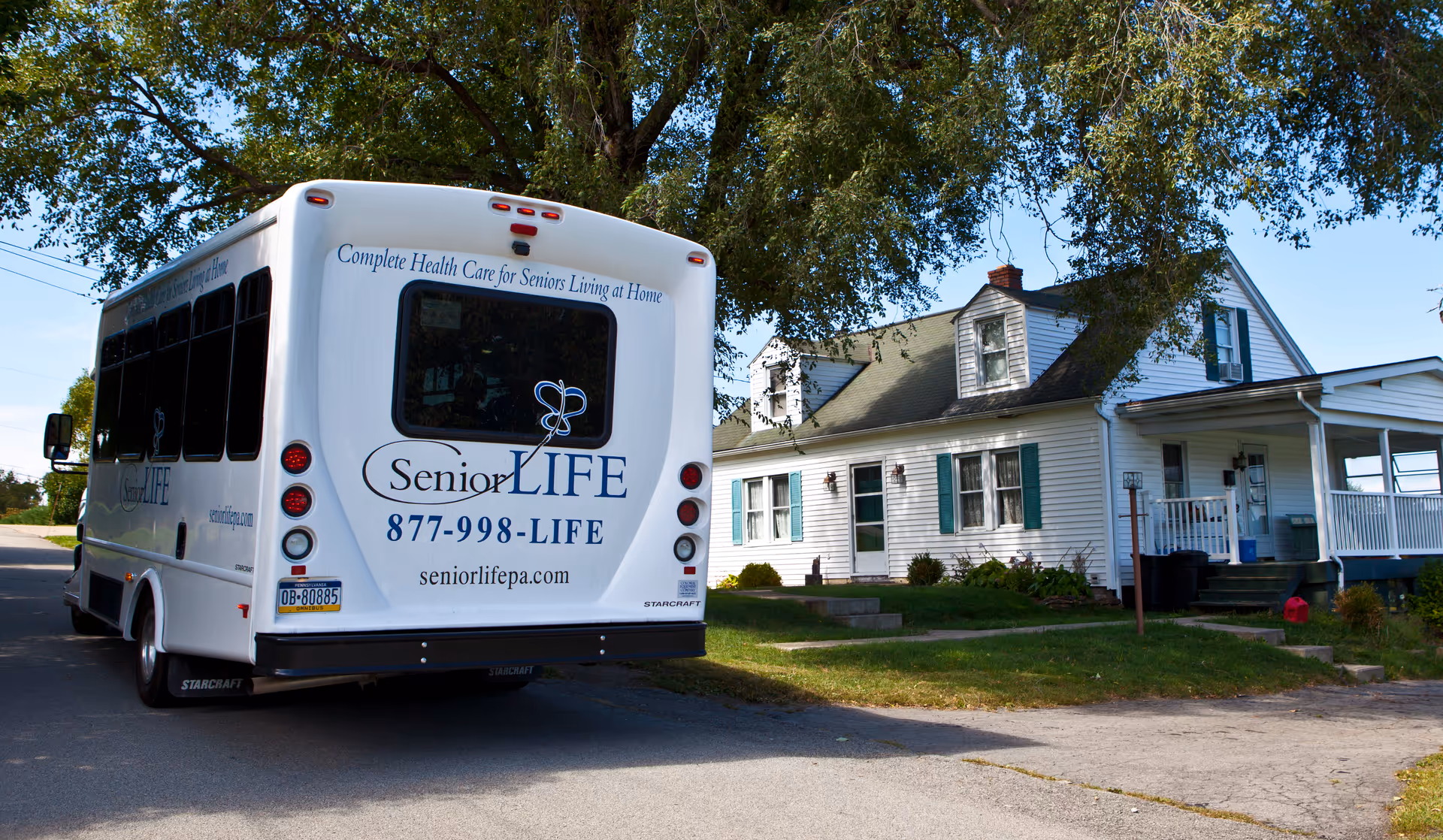 Senior LIFE shuttle parked outside a white building with a front porch.