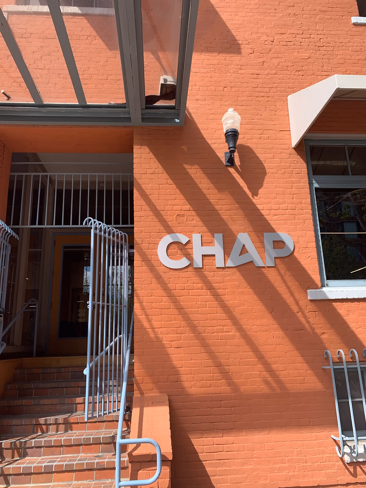 Orange brick facility entrance with CHAP lettering and metal railings leading to a doorway