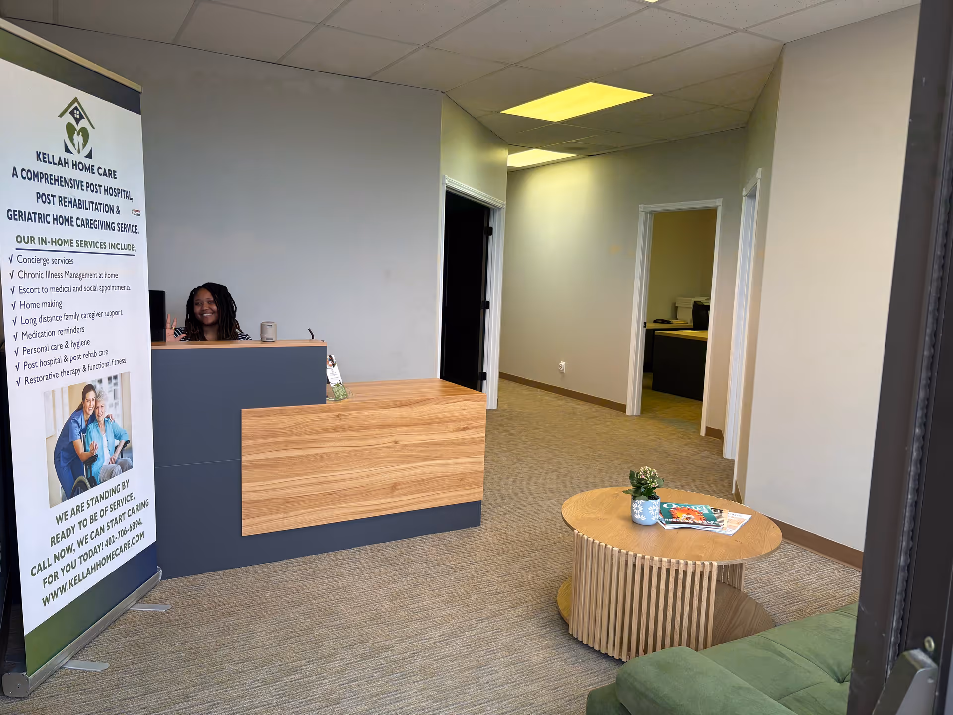 Reception desk in a lobby with a banner, couch, and round coffee table.