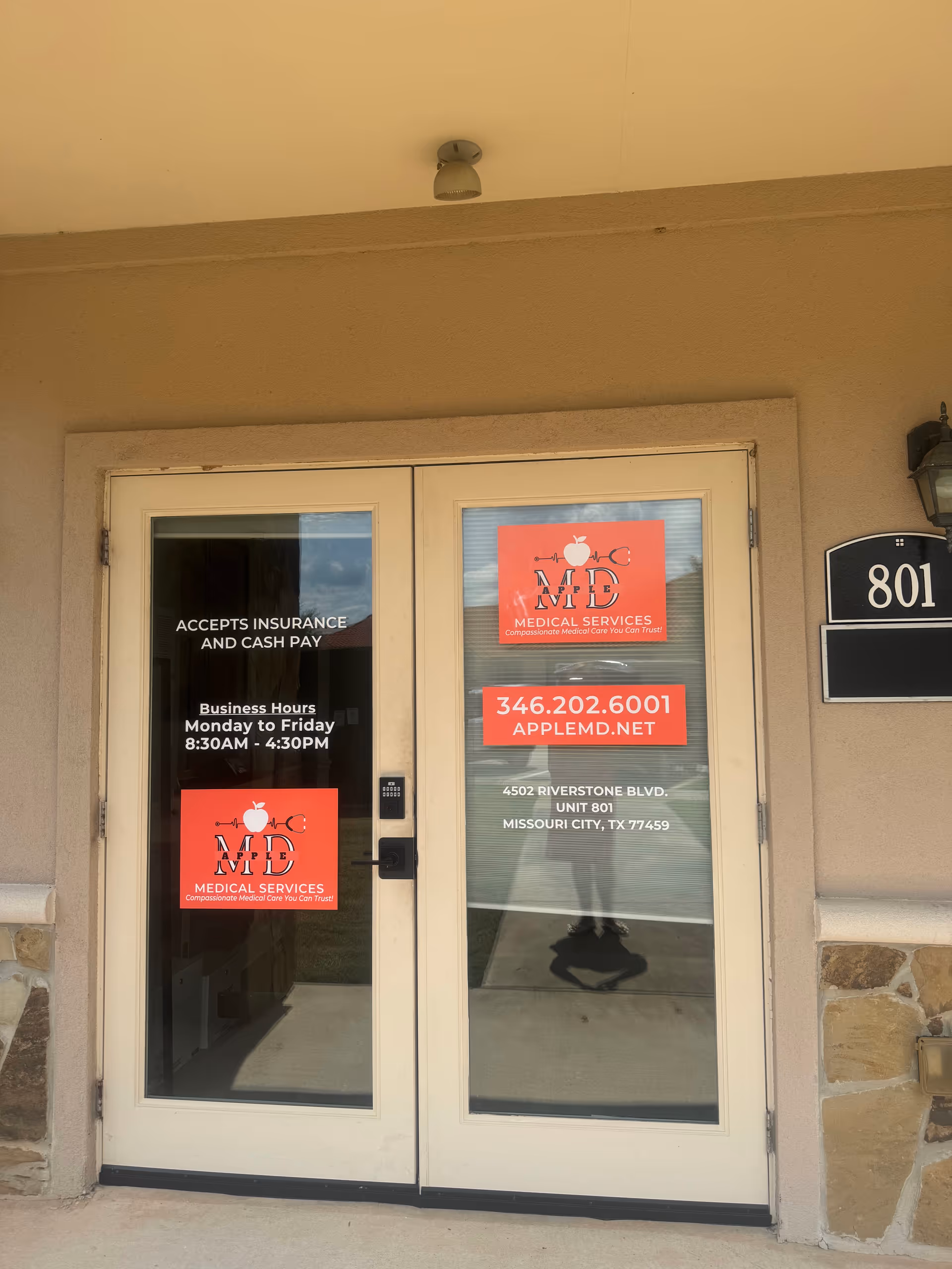 Entrance to APPLEMD Medical Services with red logo signs on glass doors.