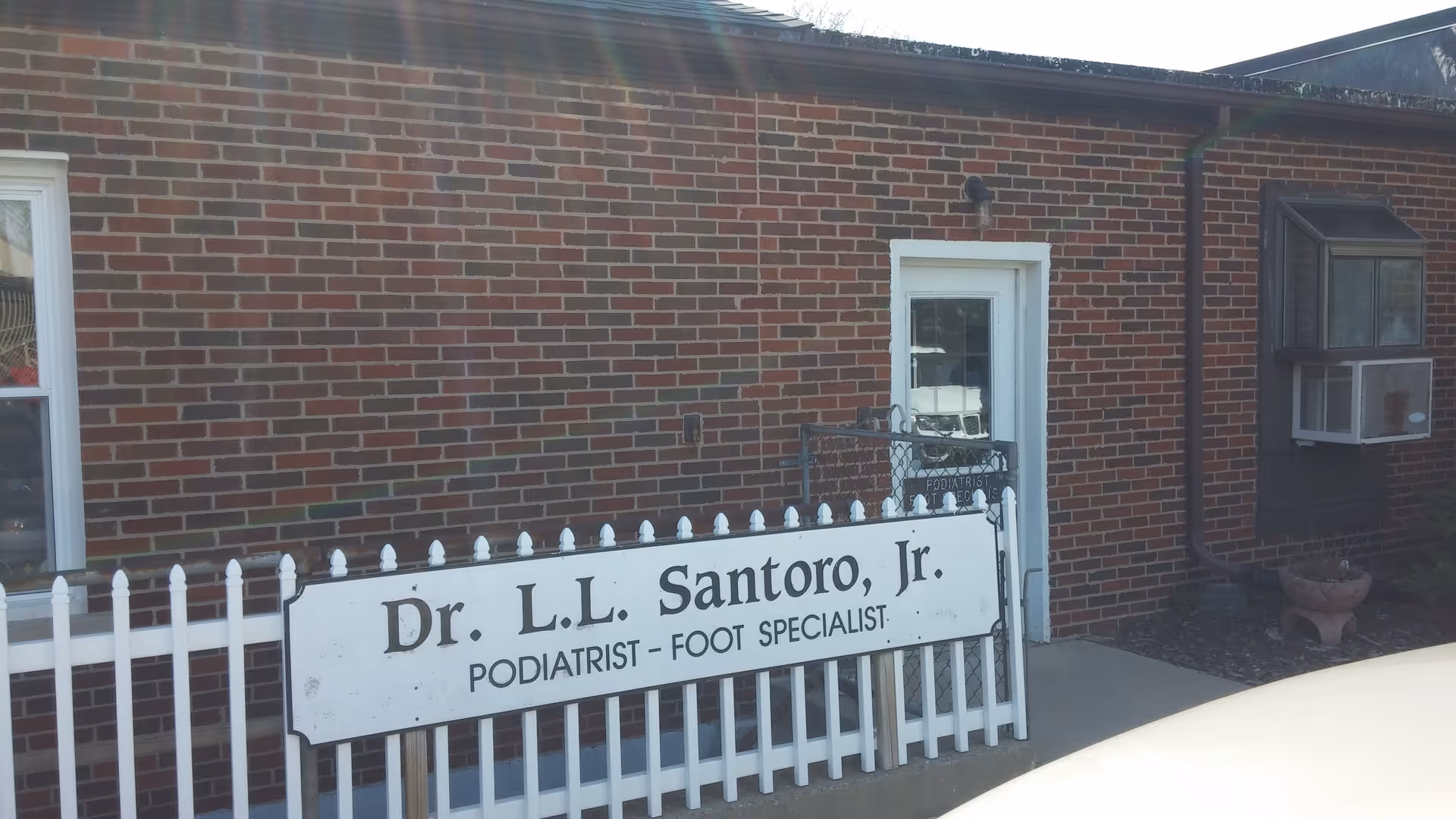 Brick building exterior with a white sign reading Dr. L.L. Santoro Jr., podiatrist.