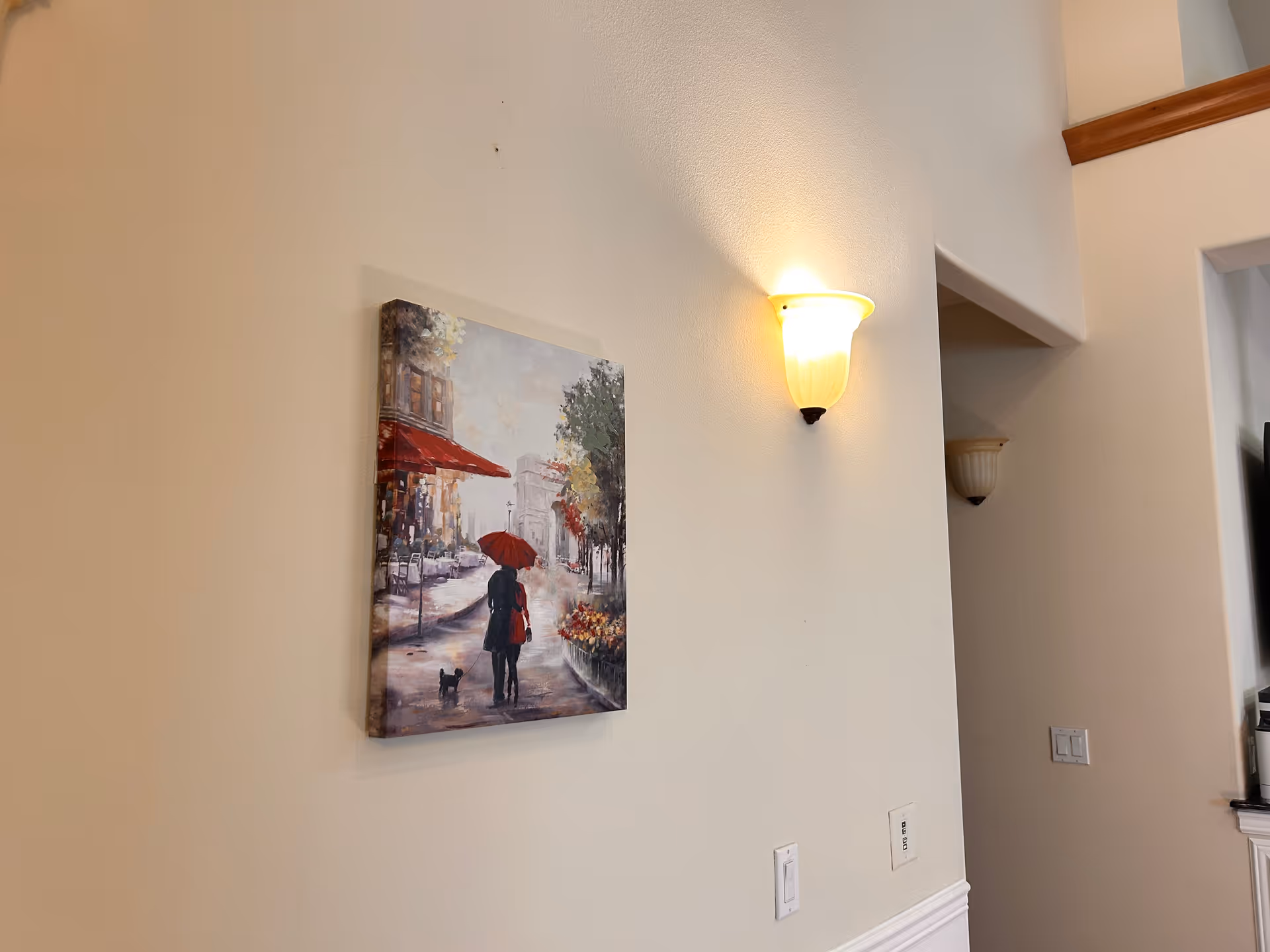 Interior hallway with wall painting and wall-mounted light, cream walls and trim.