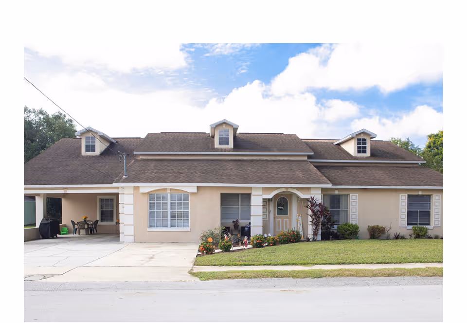 Front view of a single-story beige house with a lawn and garden.