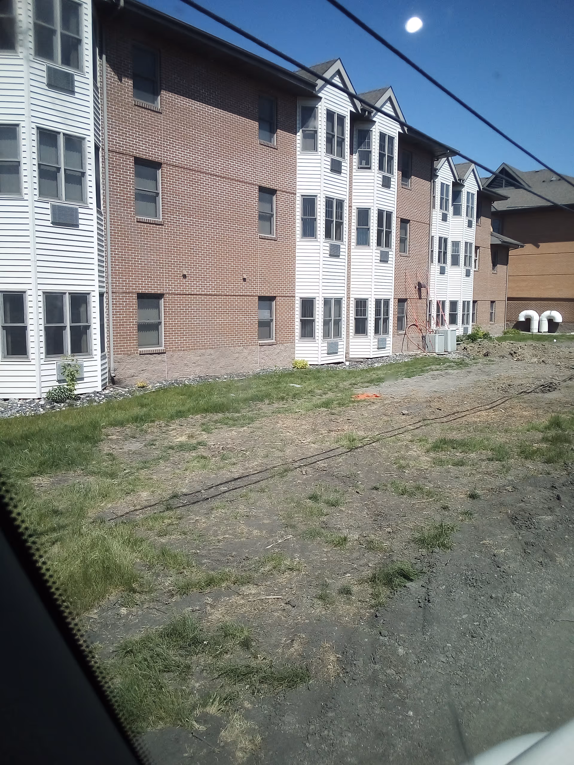 Exterior view of a multi-story brick and white siding senior living building.