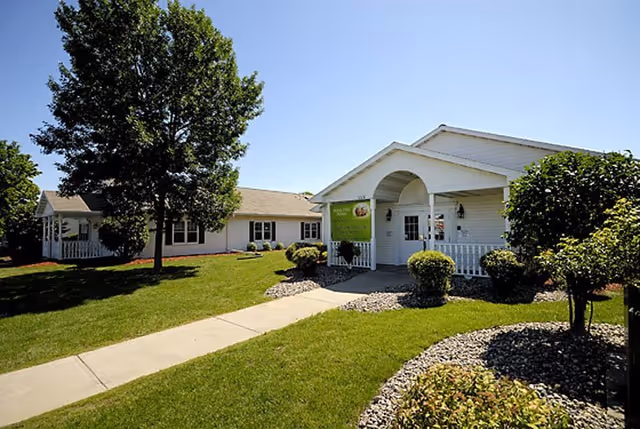 Front exterior of The Groves Assisted Living & Memory Care with lawn and walkway.