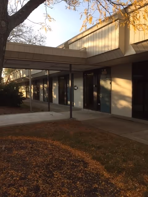 Exterior view of a single-story senior care building with a covered walkway.