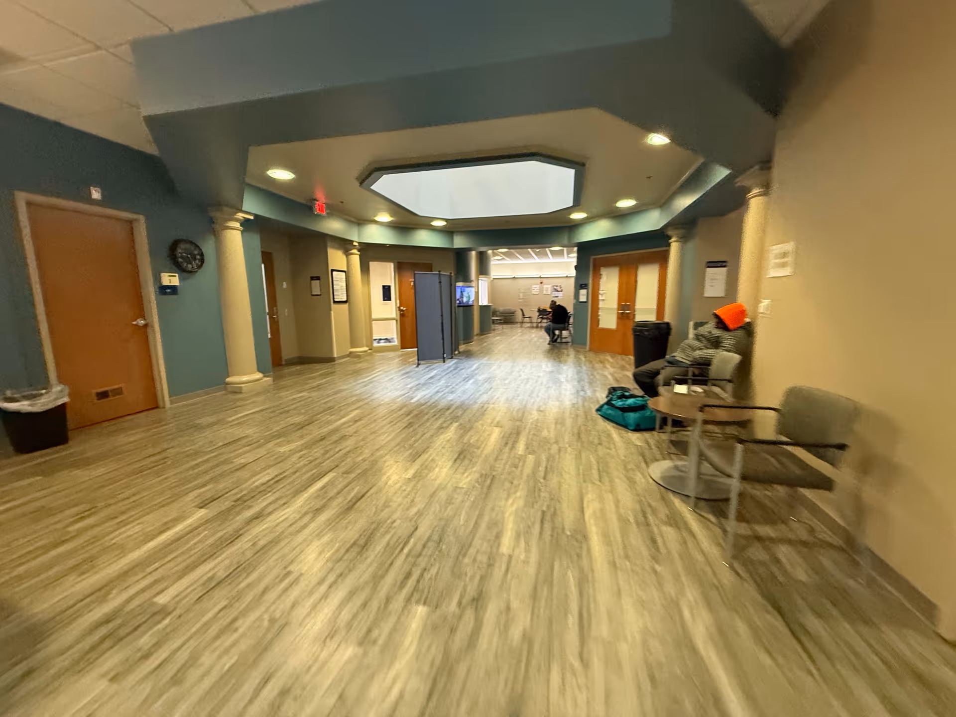 Wide interior hallway of a senior living facility with seating and doors along the walls.