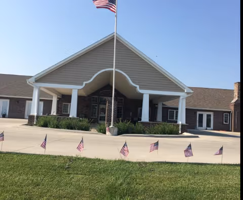 Front view of Villas of Holly Brook Newton exterior with flagpole and small flags.