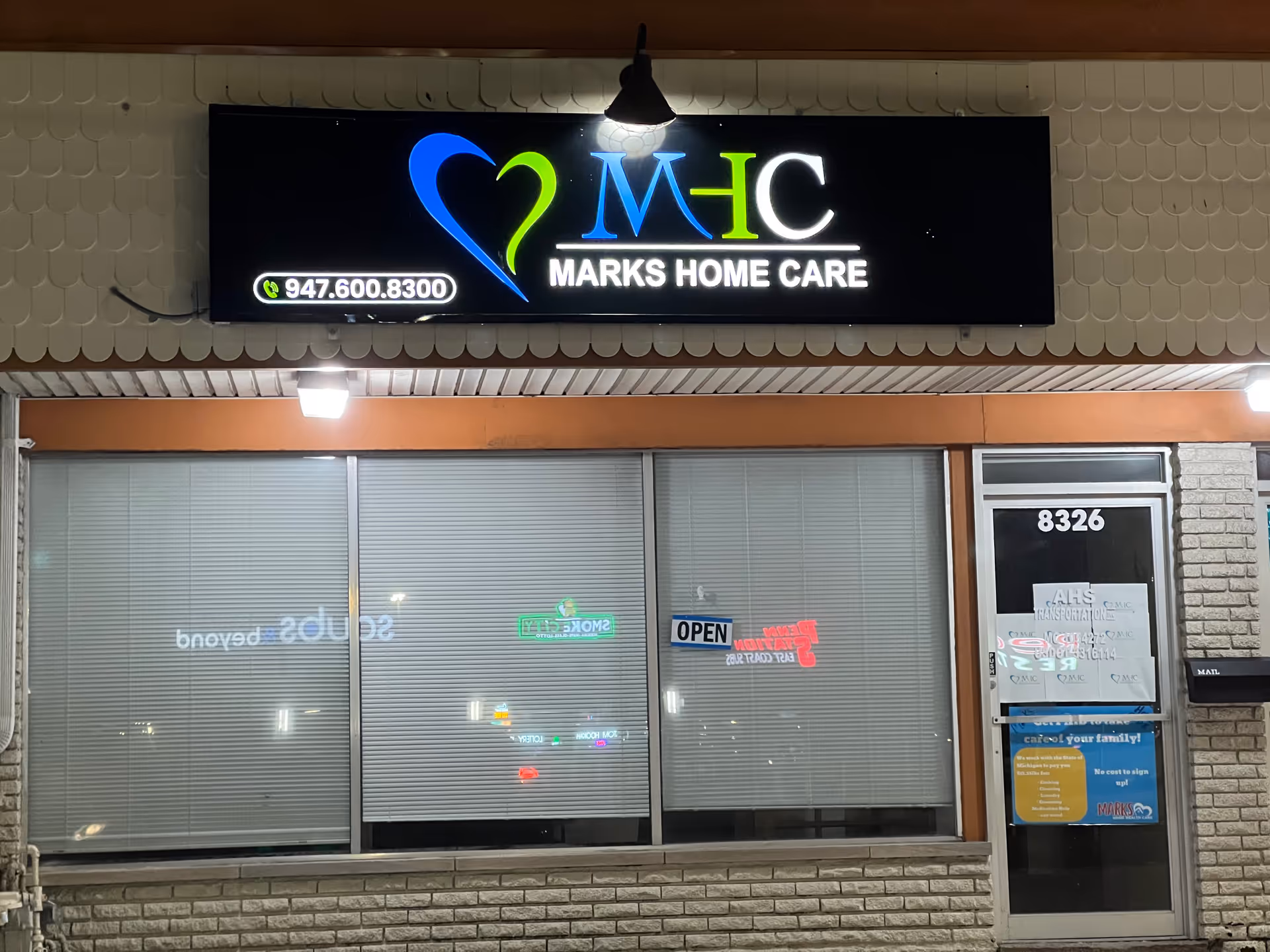 Storefront of Marks Home Care with illuminated logo sign above large glass windows.