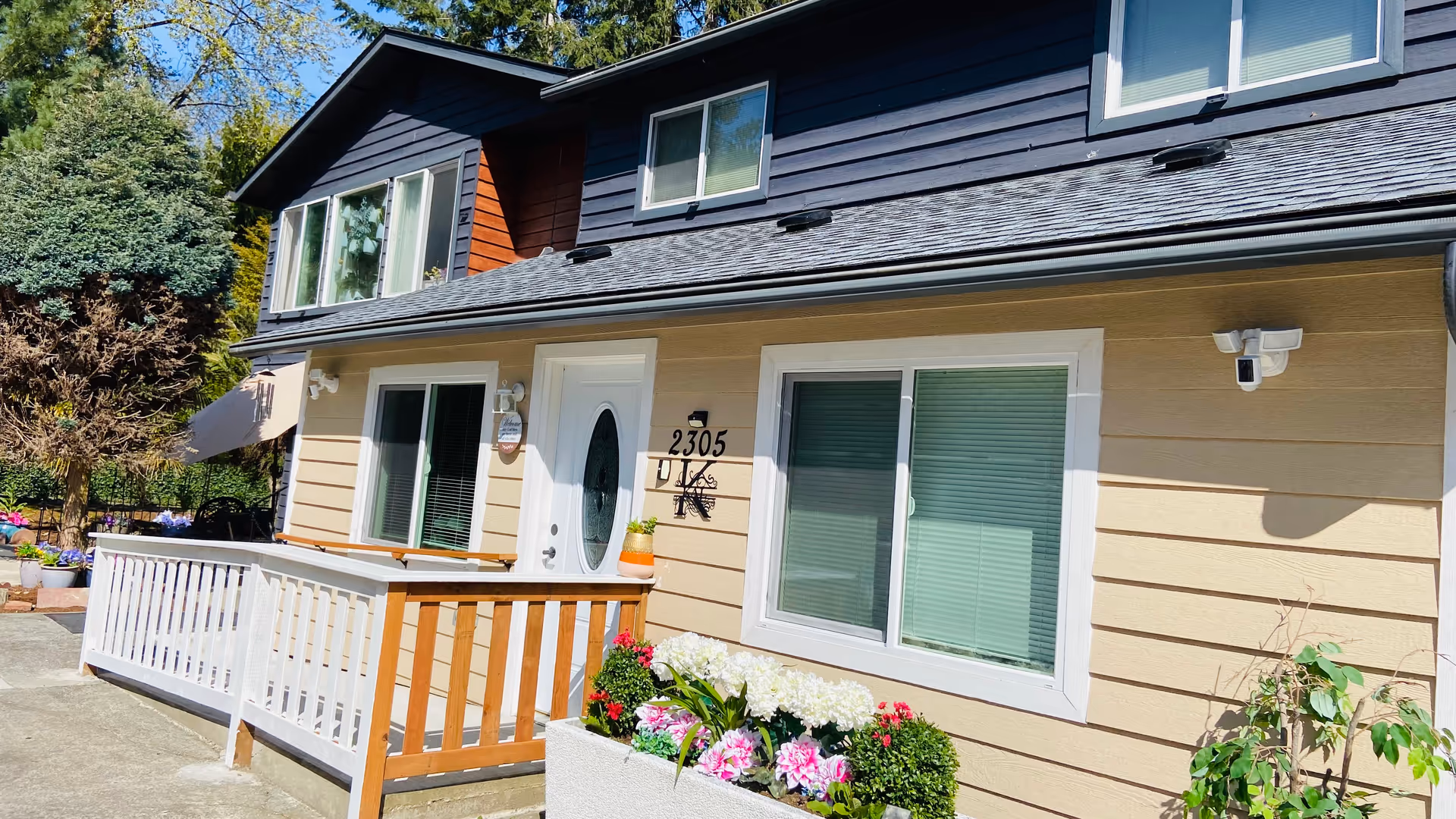 Exterior of Blissful Living AFH building with porch, windows, and blooming flower planters