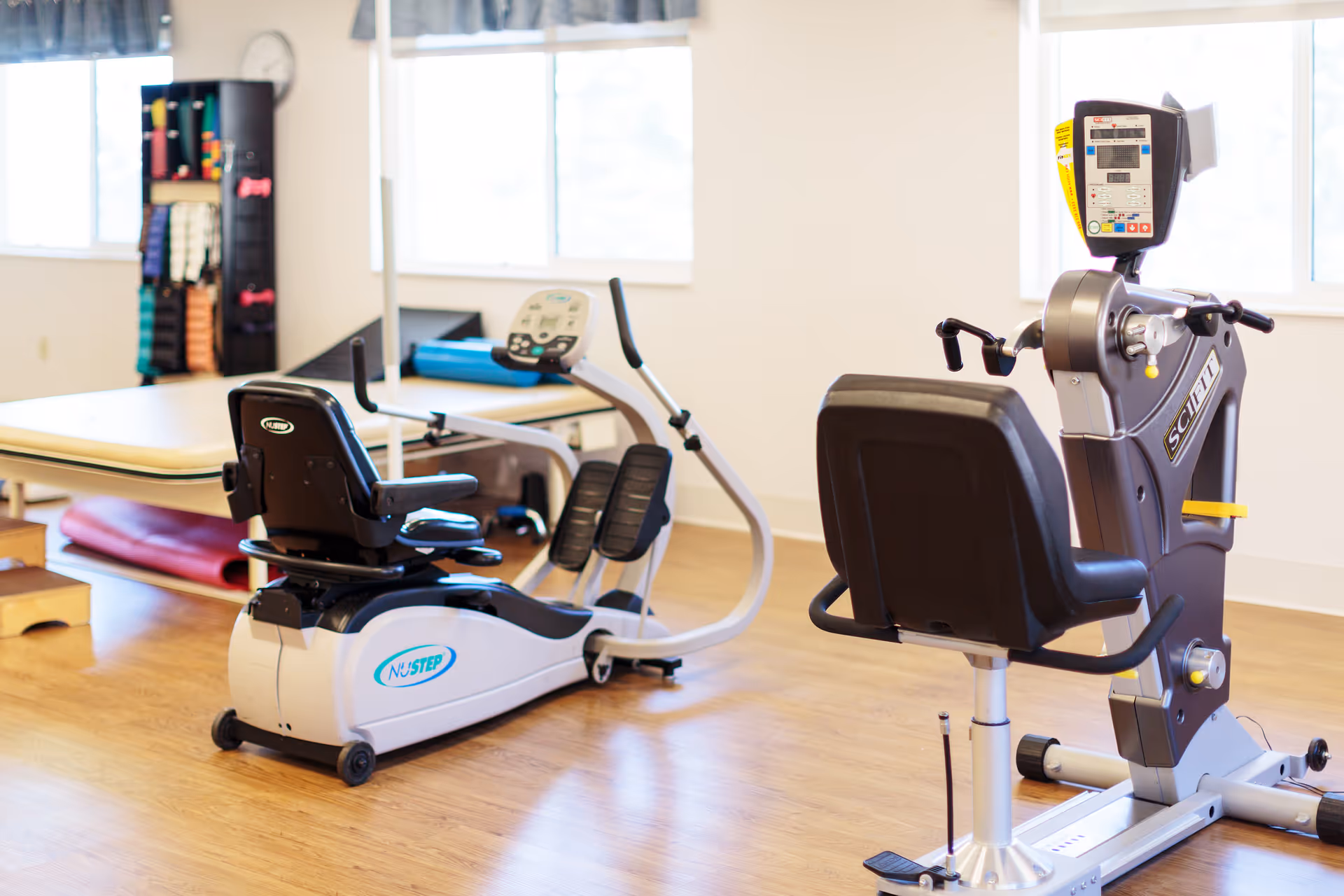 Rehabilitation gym with exercise machines and natural light from windows.