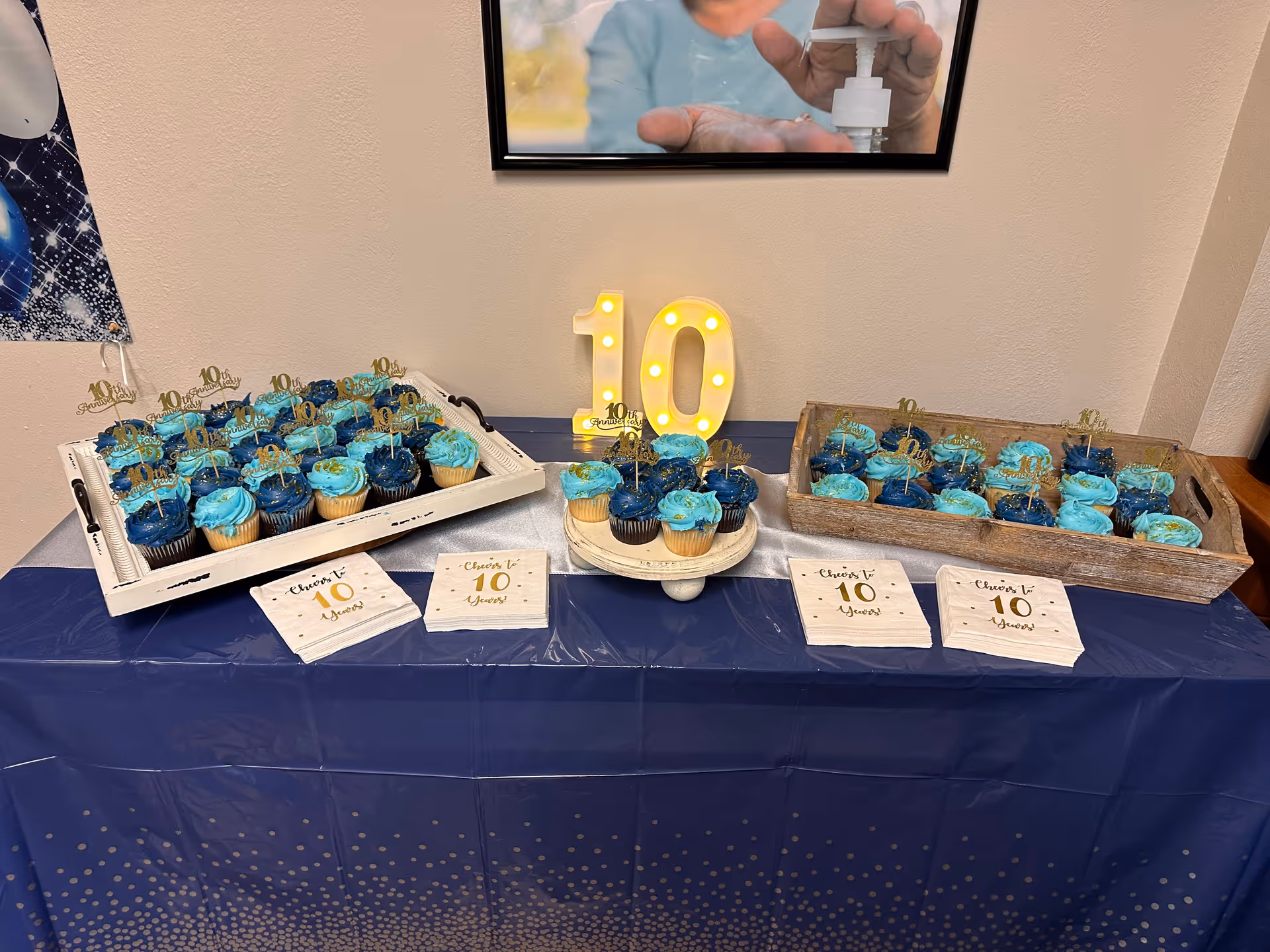 Table of blue cupcakes and a glowing 10 centerpiece in a senior care celebration setup.