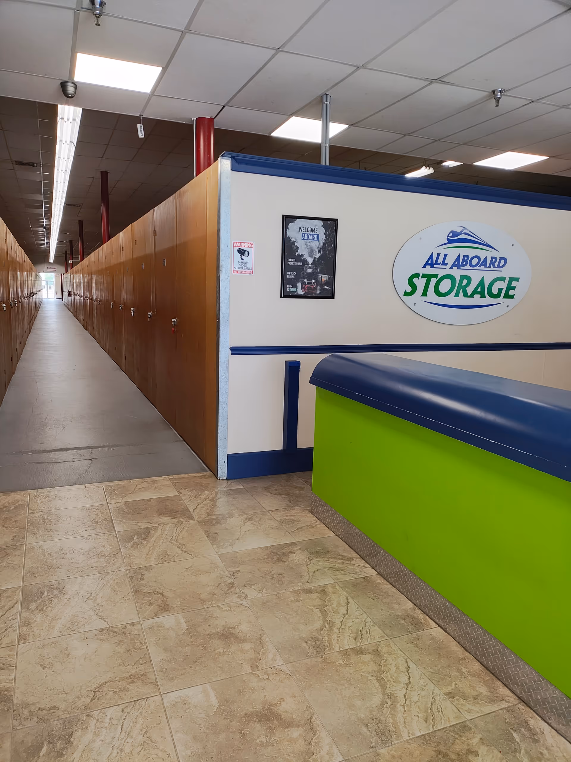 Long hallway with rows of wooden lockers along left and a lime-green counter on right.