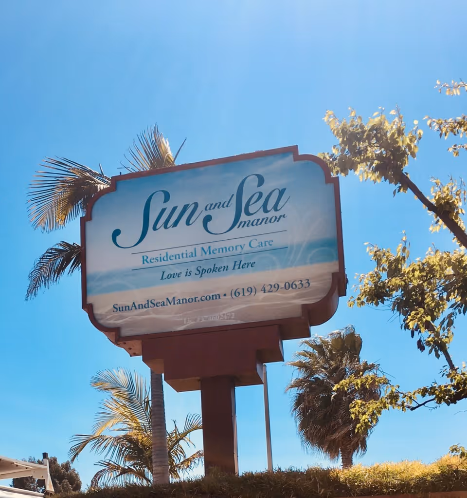 Sun and Sea Manor sign against a clear blue sky with palm trees