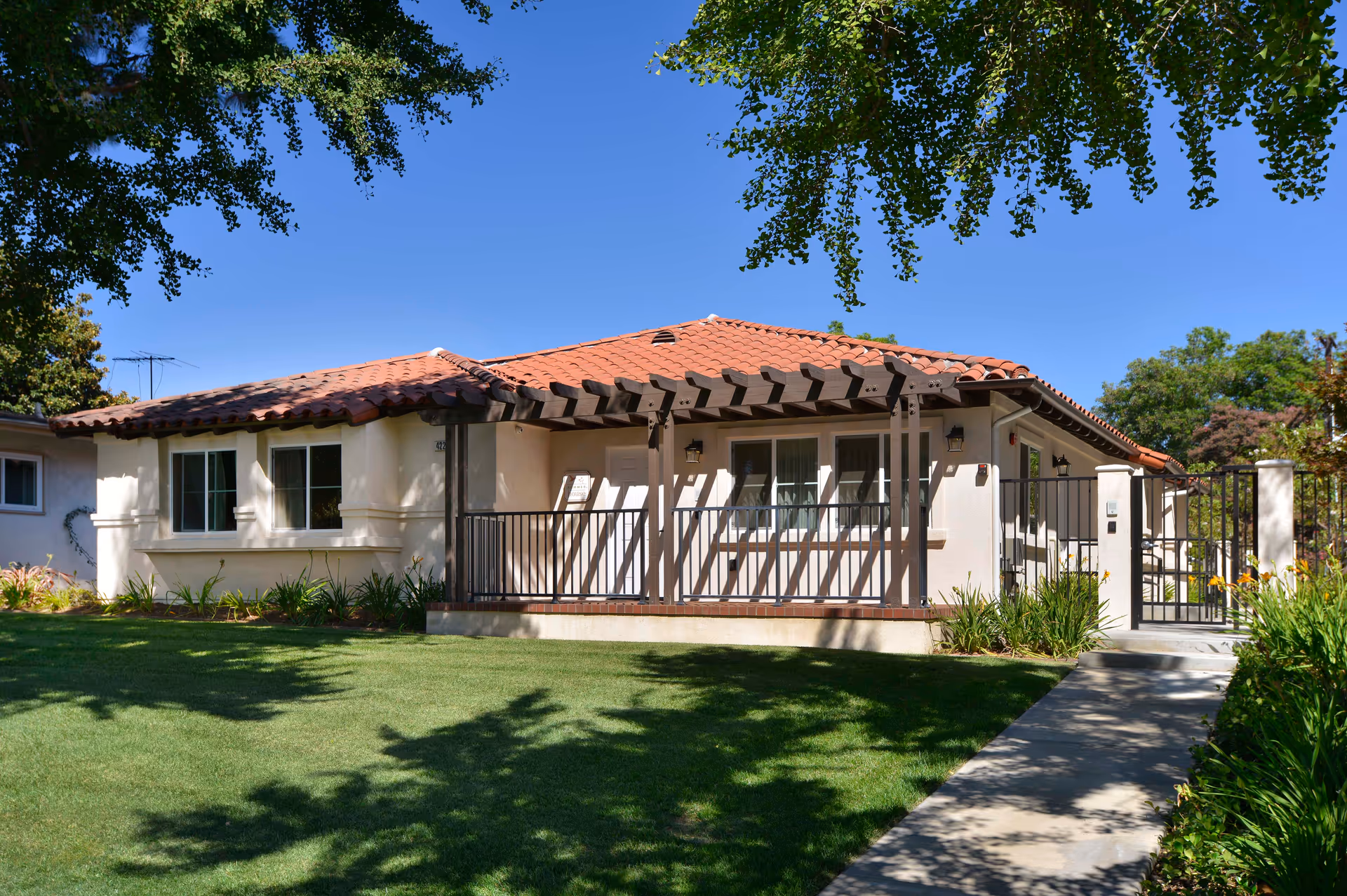 Single-story retirement community building with a red-tiled roof, porch, and manicured lawn.