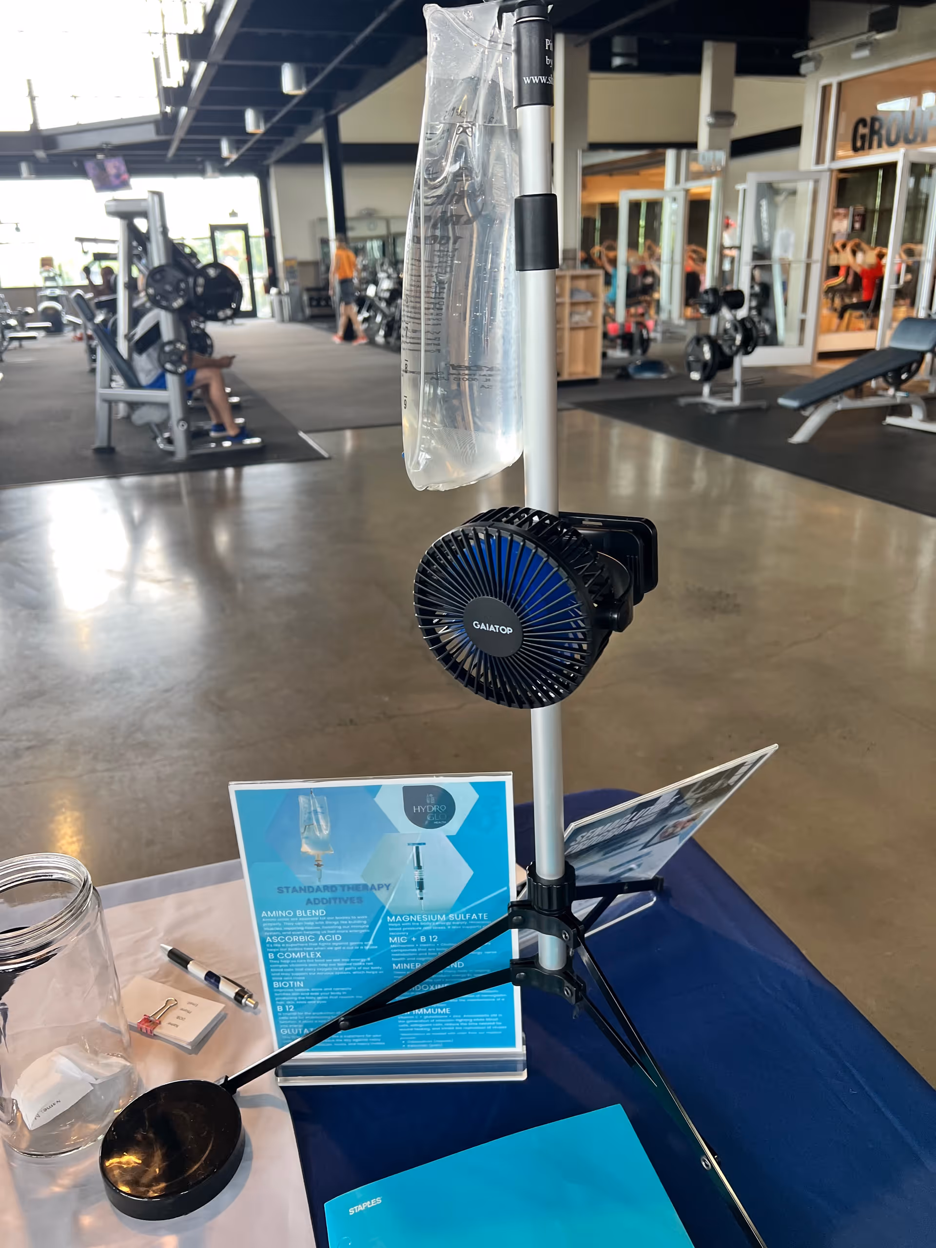 Indoor gym area with weight machines, benches, and people exercising.