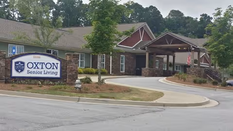 Exterior view of a senior living facility with a covered entrance and landscaping.