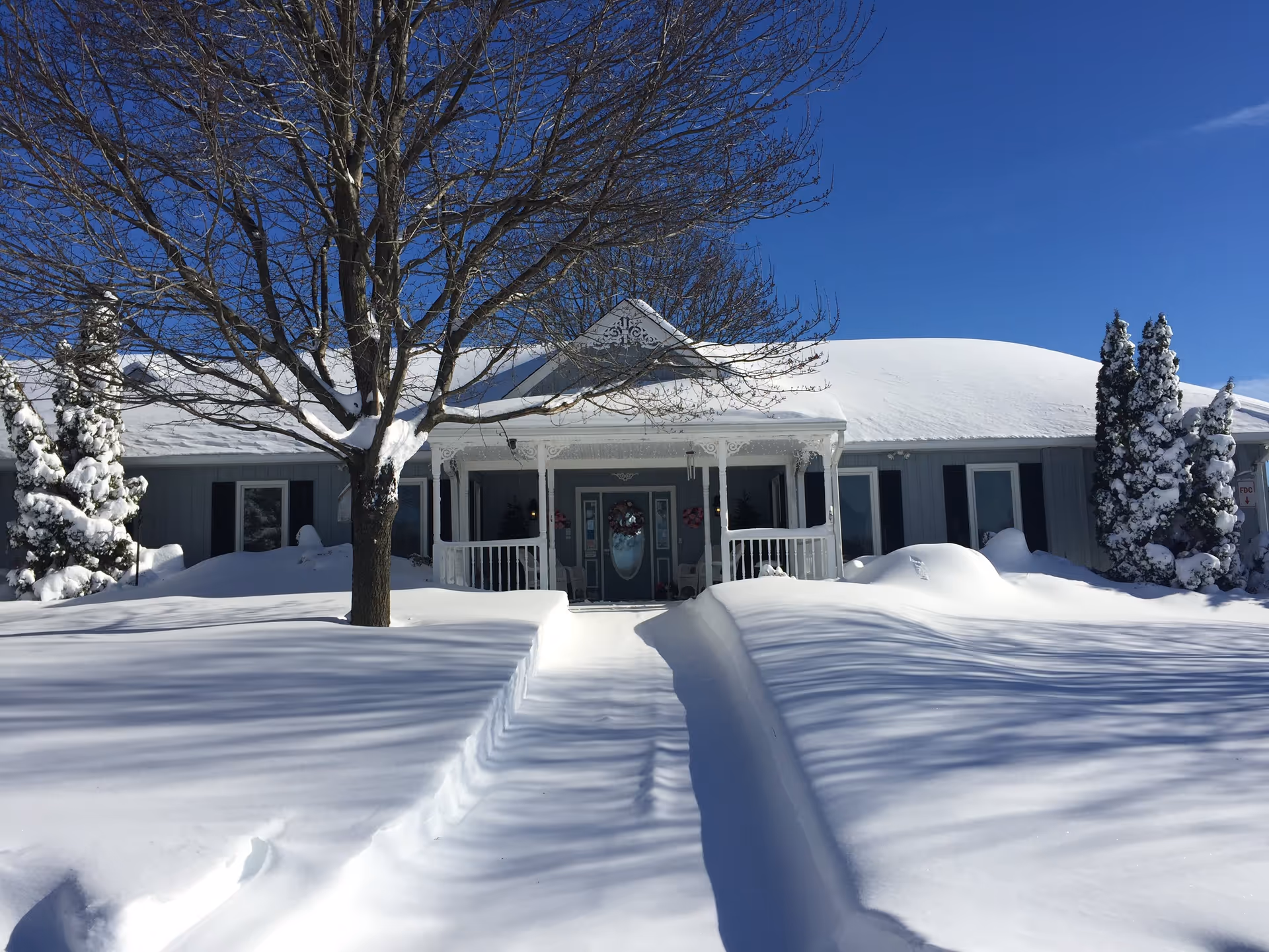Snow-covered single-story building with a front porch and a clear path to the entrance.