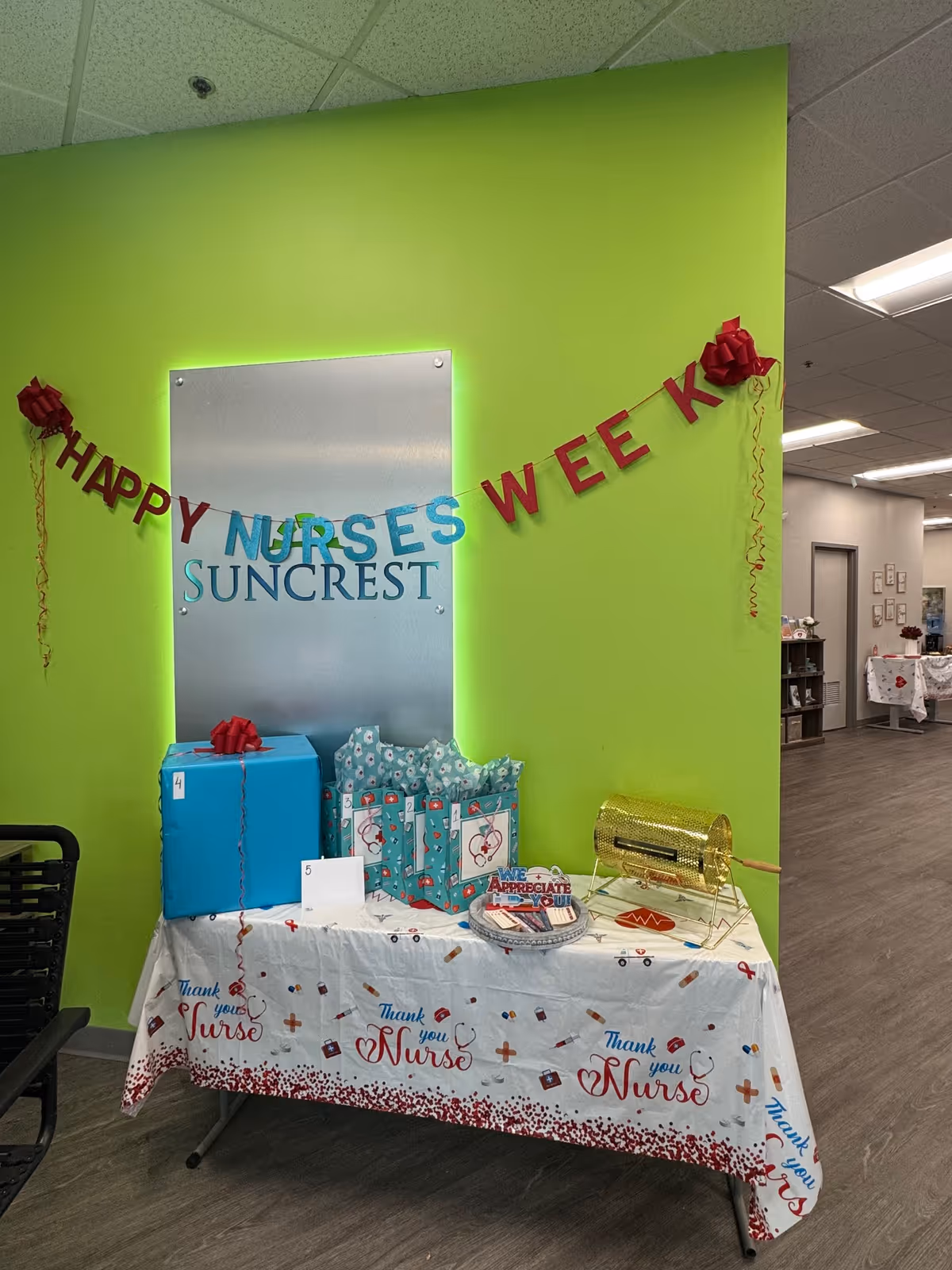 Bright lime wall with 'Happy Nurses Week' banner and gift table inside a facility.