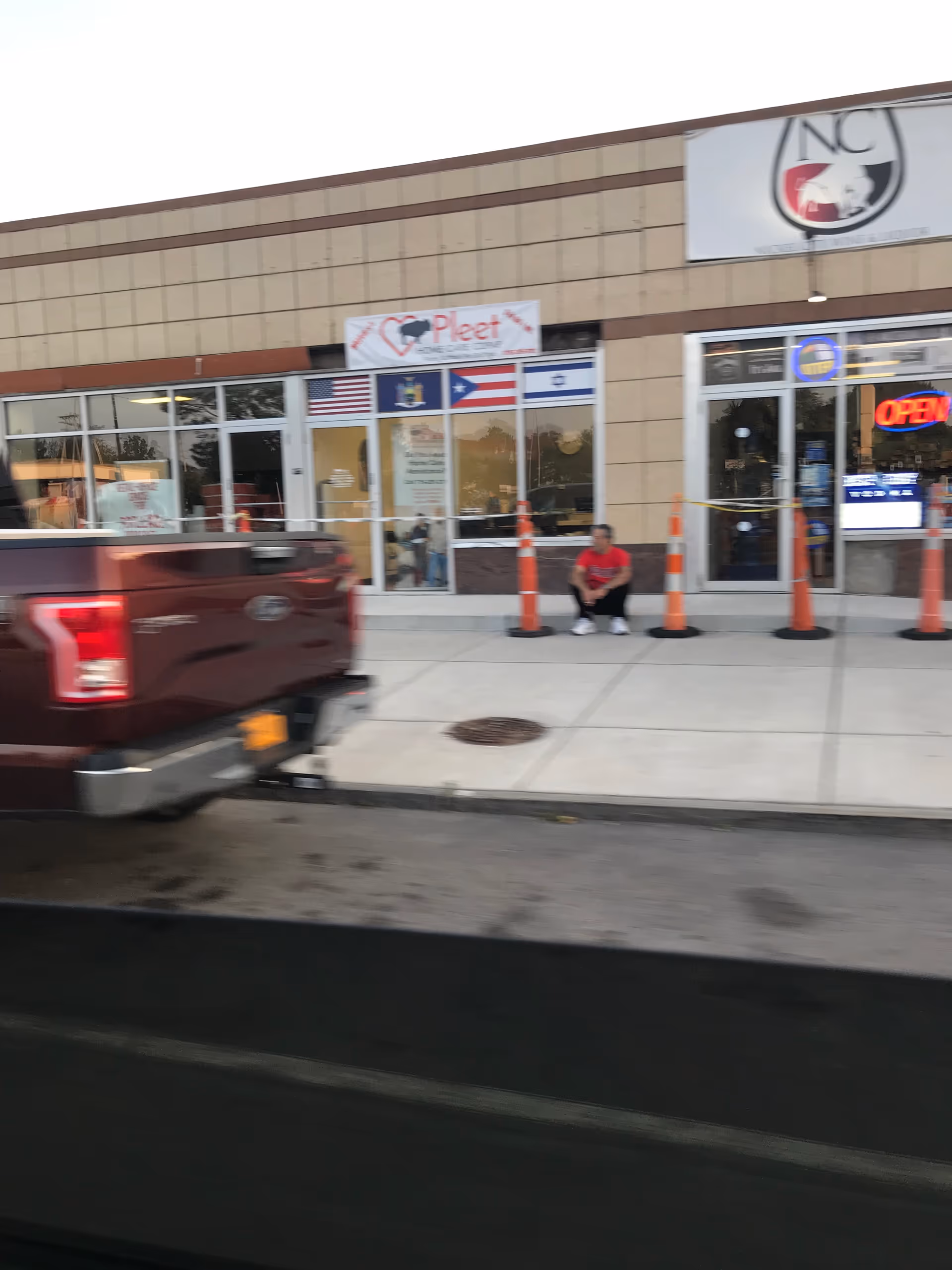 Storefront of Pleet Home Care CDPAP with a man sitting outside and a pickup truck.